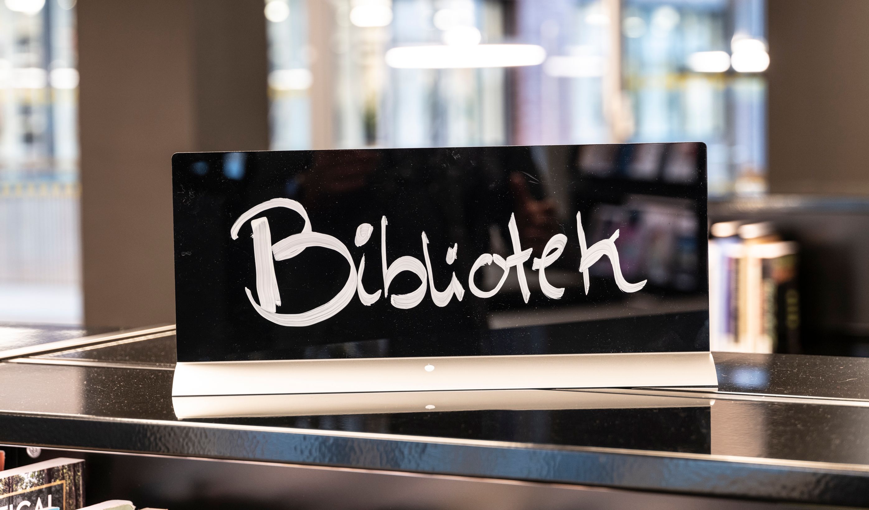 A black sign reading "Bibliotek" (Library) in white script.