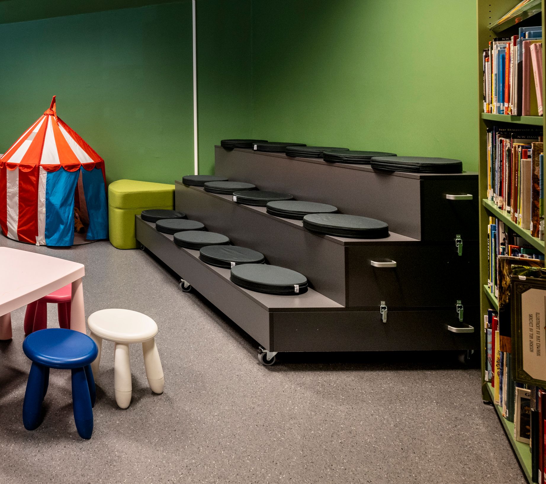 et barnerom i et bibliotek med bord og stoler.