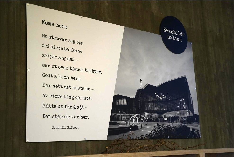 A poster on a wall shows a Norwegian poem next to a black and white photo of a modern building, with a circular "Svanhilds salong" sign above.