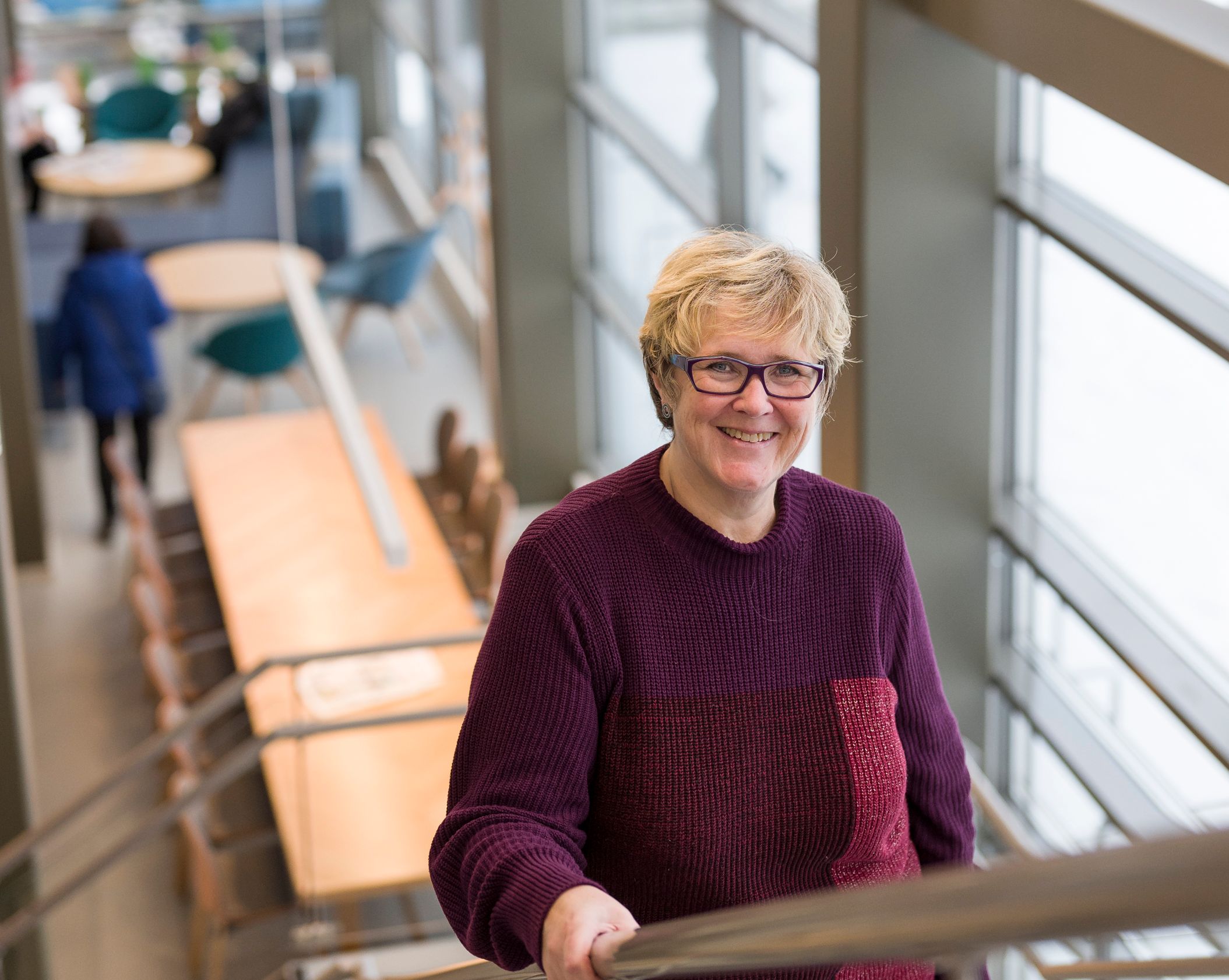 en kvinne i en lilla genser står på et sett med trapper