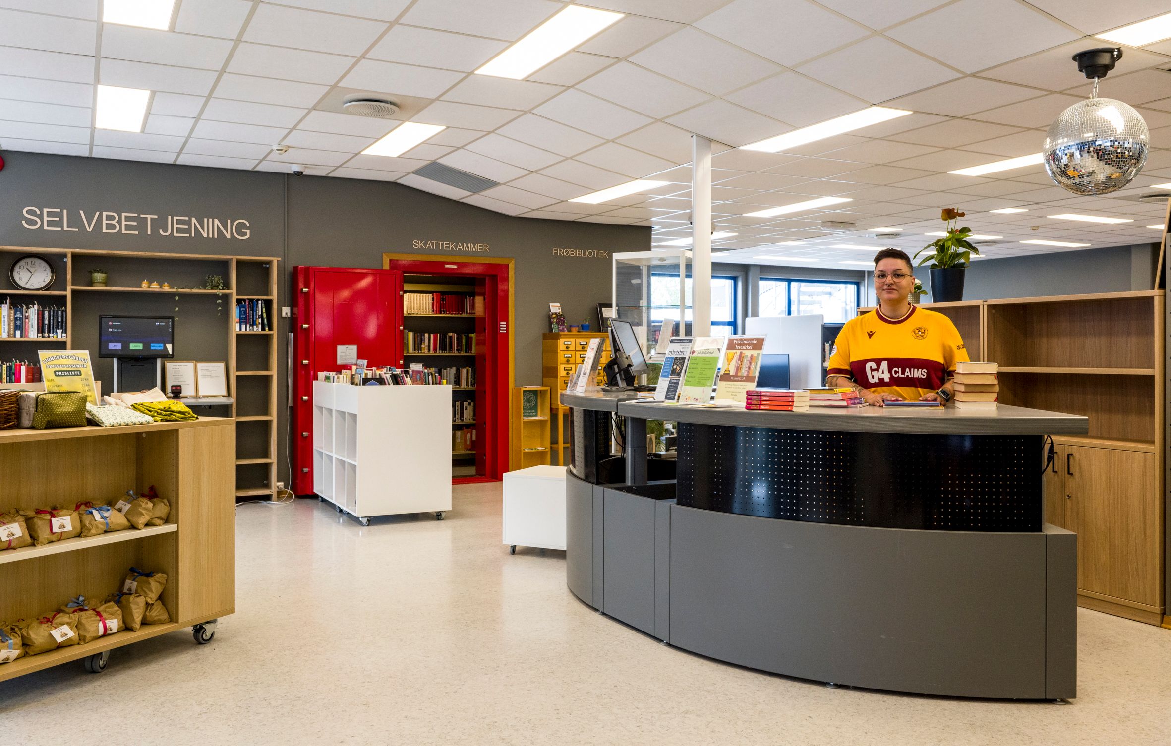 en skranke i et bibliotek som det står en smilende dame bak