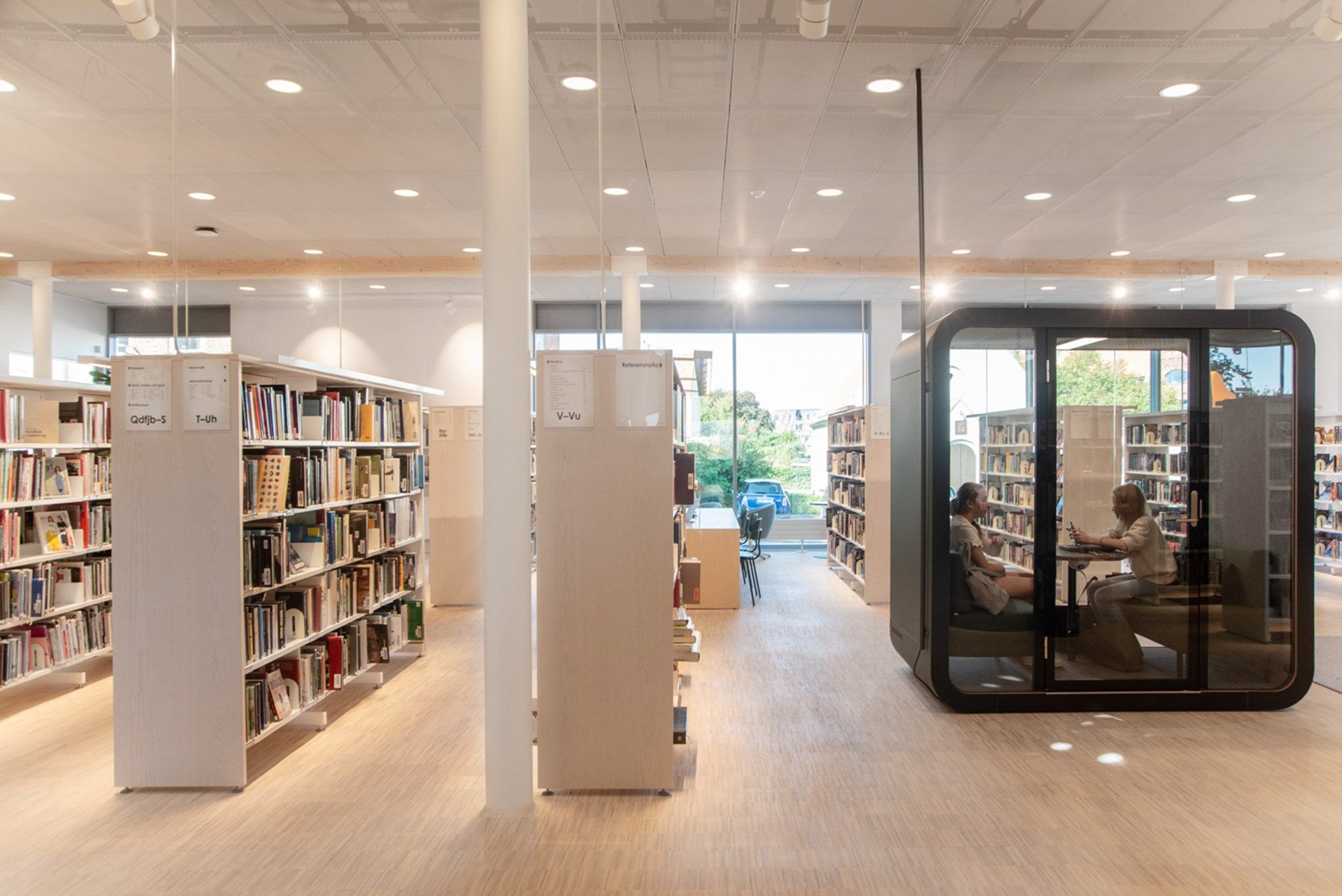 et bibliotek med en møteboks med to mennesker inni