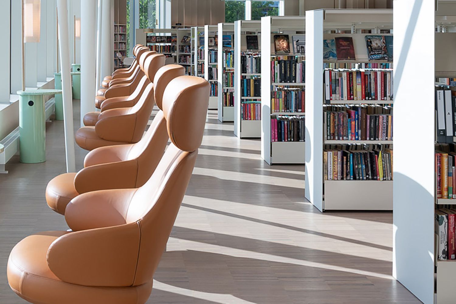 et bibliotek med mange lenestoler foran store vinduer