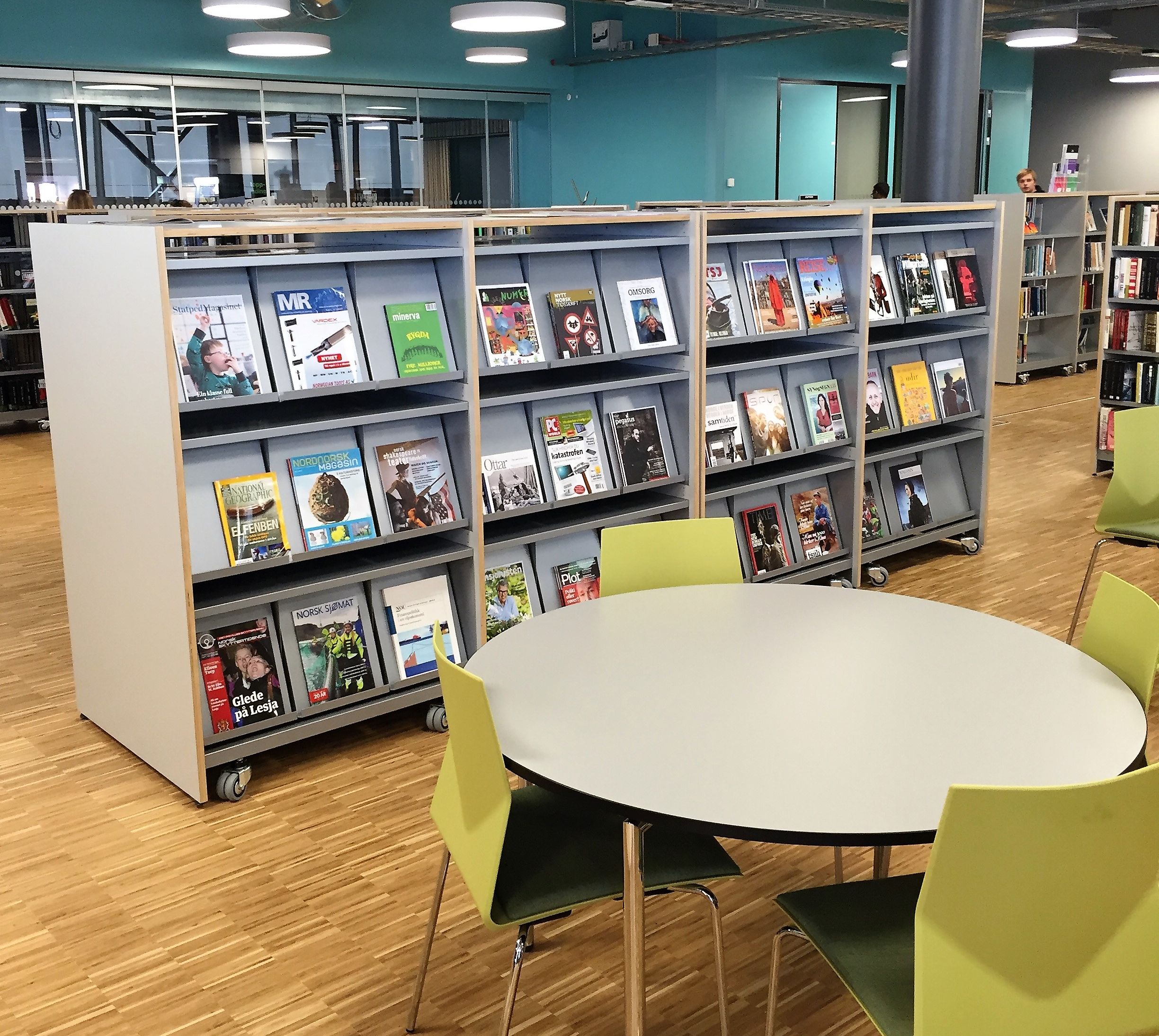 et bibliotek med et bord og stoler og bøker på hyllene.