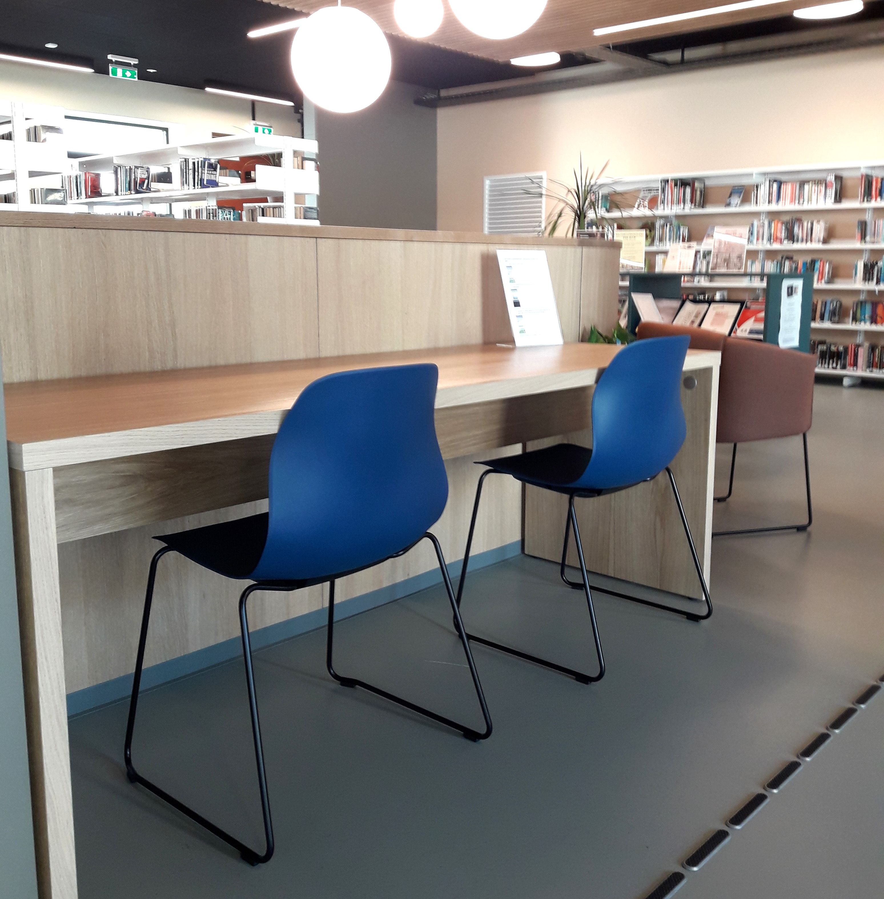 to blå stoler sitter ved et skrivebord på et bibliotek