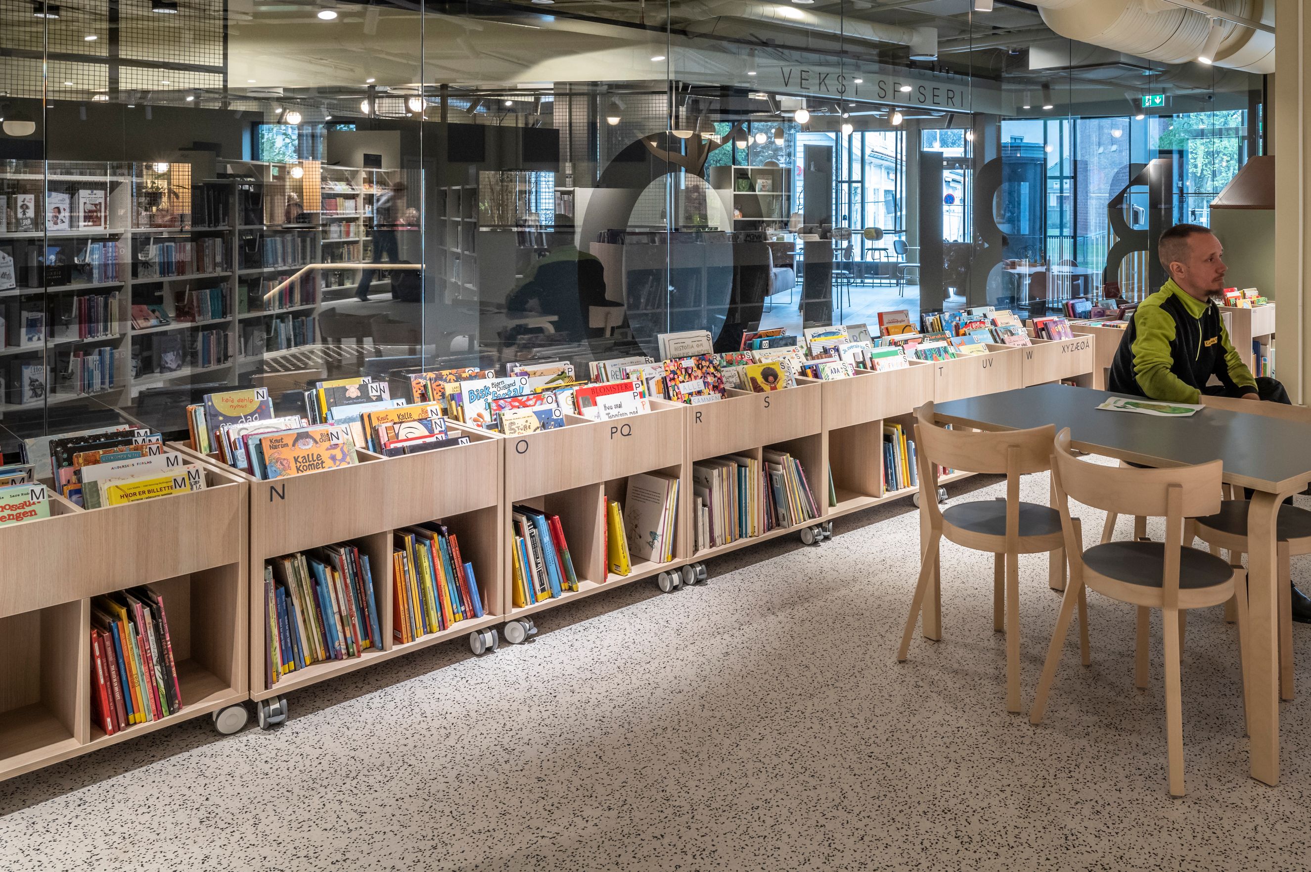 en mann sitter ved et bord på et bibliotek.