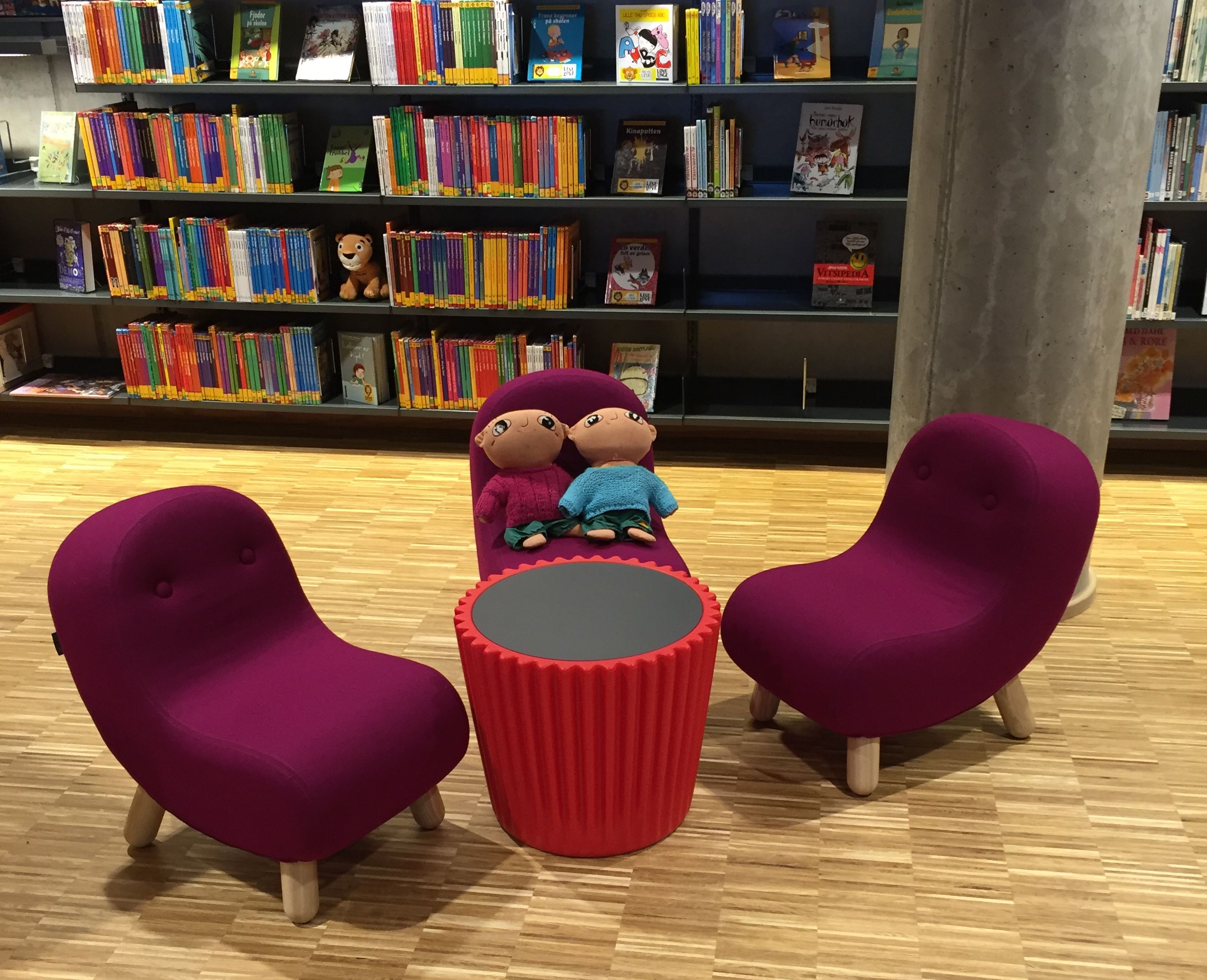 to lilla stoler og et rødt bord i et bibliotek med fylte dyr på dem.