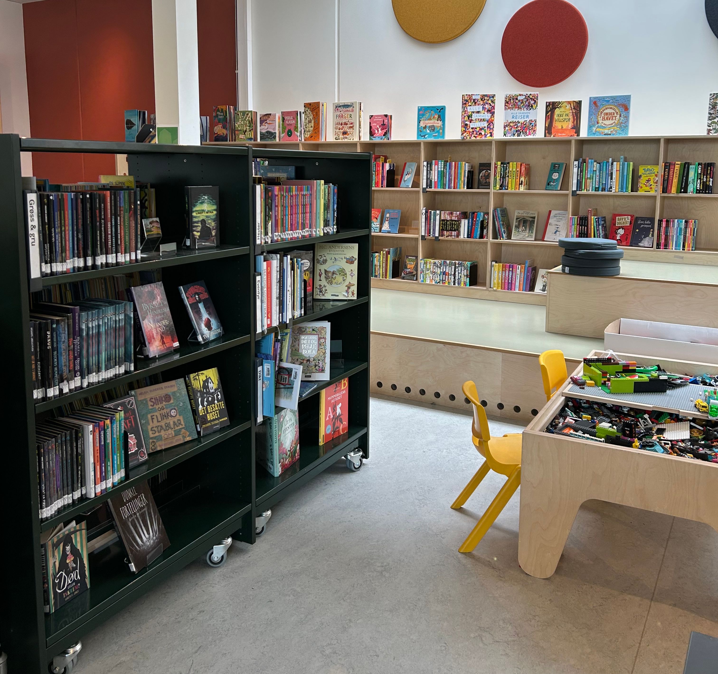et bibliotek med lave bokreoler og barnemøbler