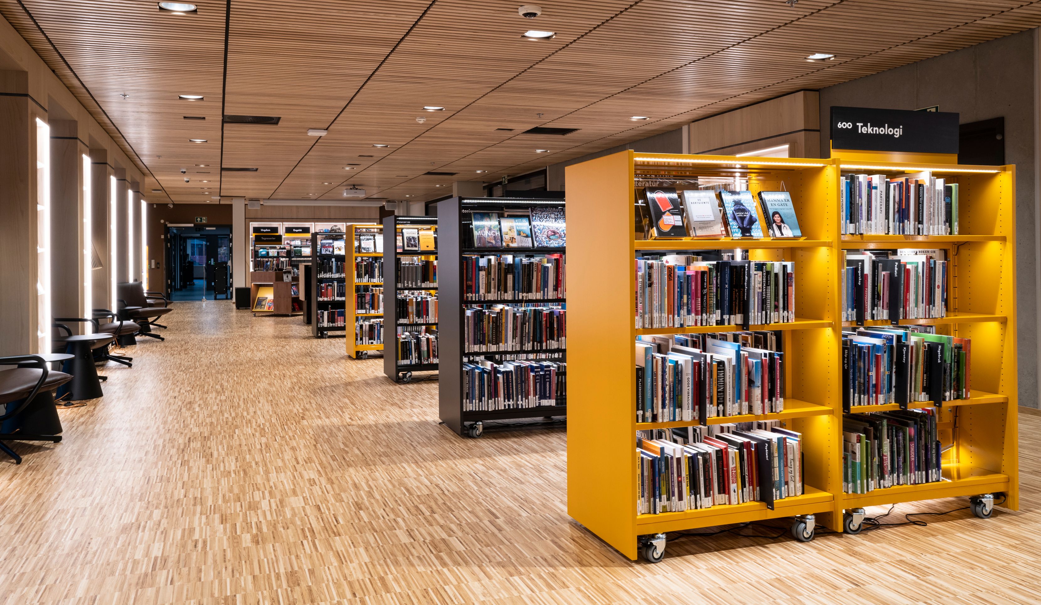 et bibliotek med mange bøker på hyllene og et tregulv.