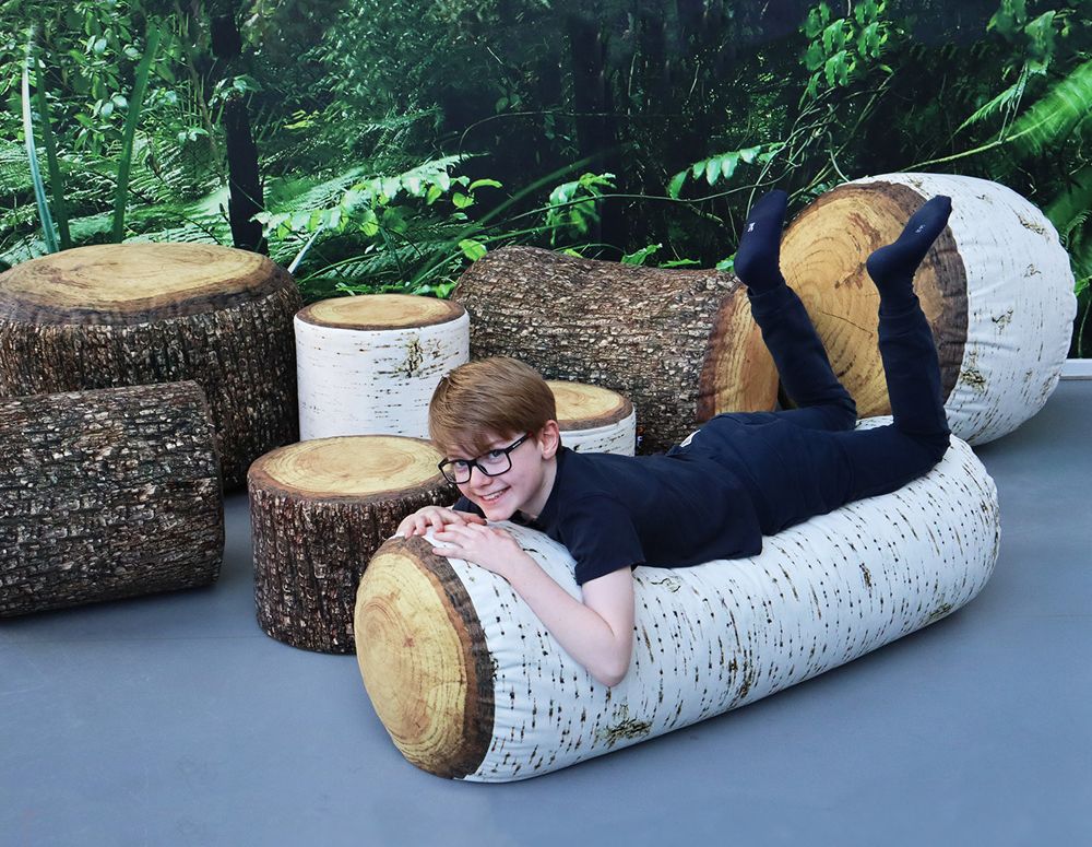 en ung gutt ligger på en bønnebag-stol formet som en tømmerstokk.