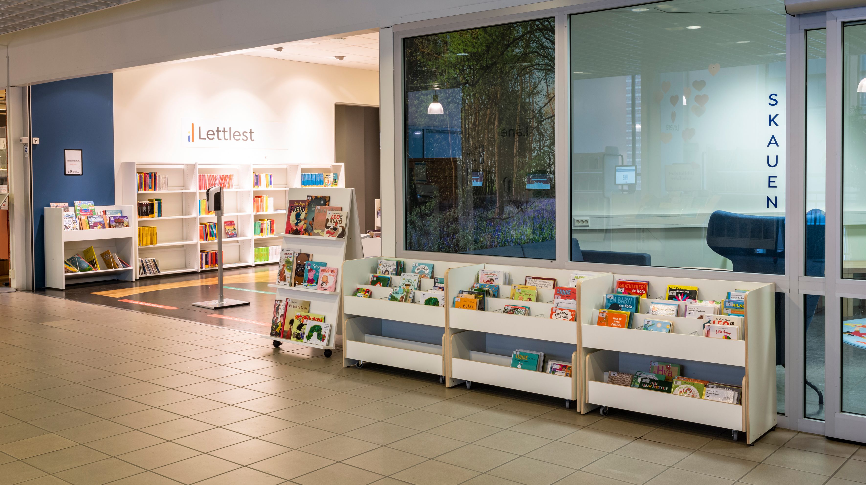 et bibliotek med mange bøker på hyllene og et stort vindu.