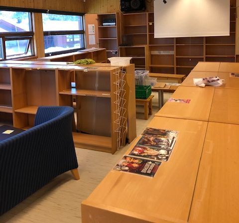an empty room with a projector screen and books on the tables