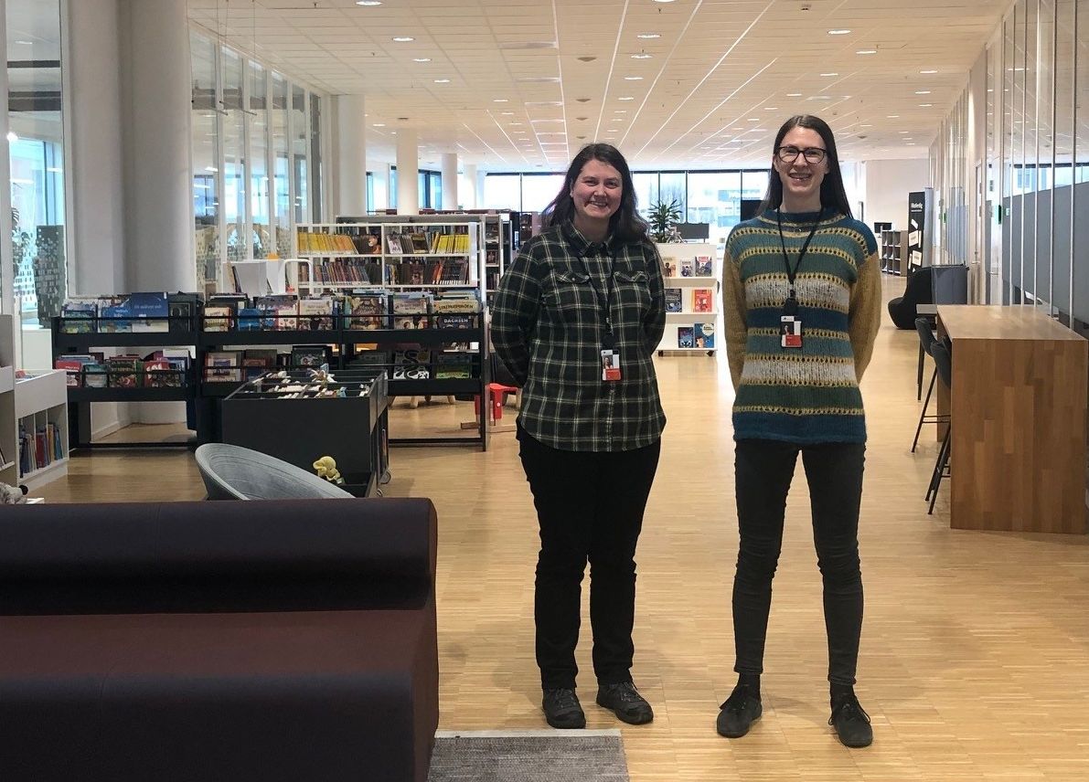 to kvinner står under et skilt som sier bibliotek