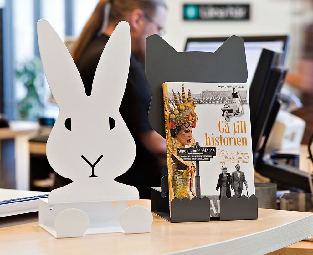 en bok står i et metallstativ formet som en ulv med et kaninstativ foran