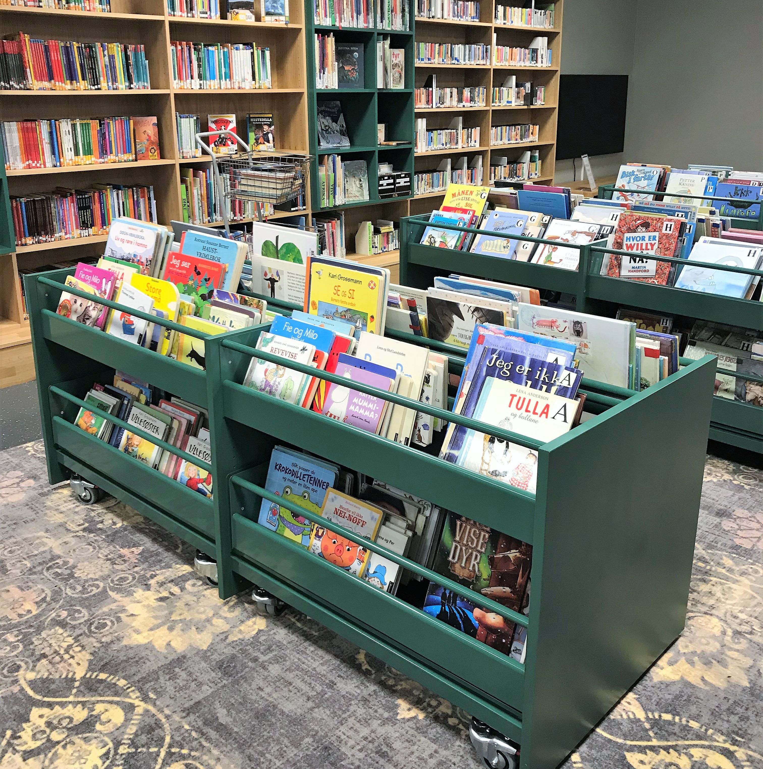 et bibliotek fylt med mange barnebøker på grønne hyller.