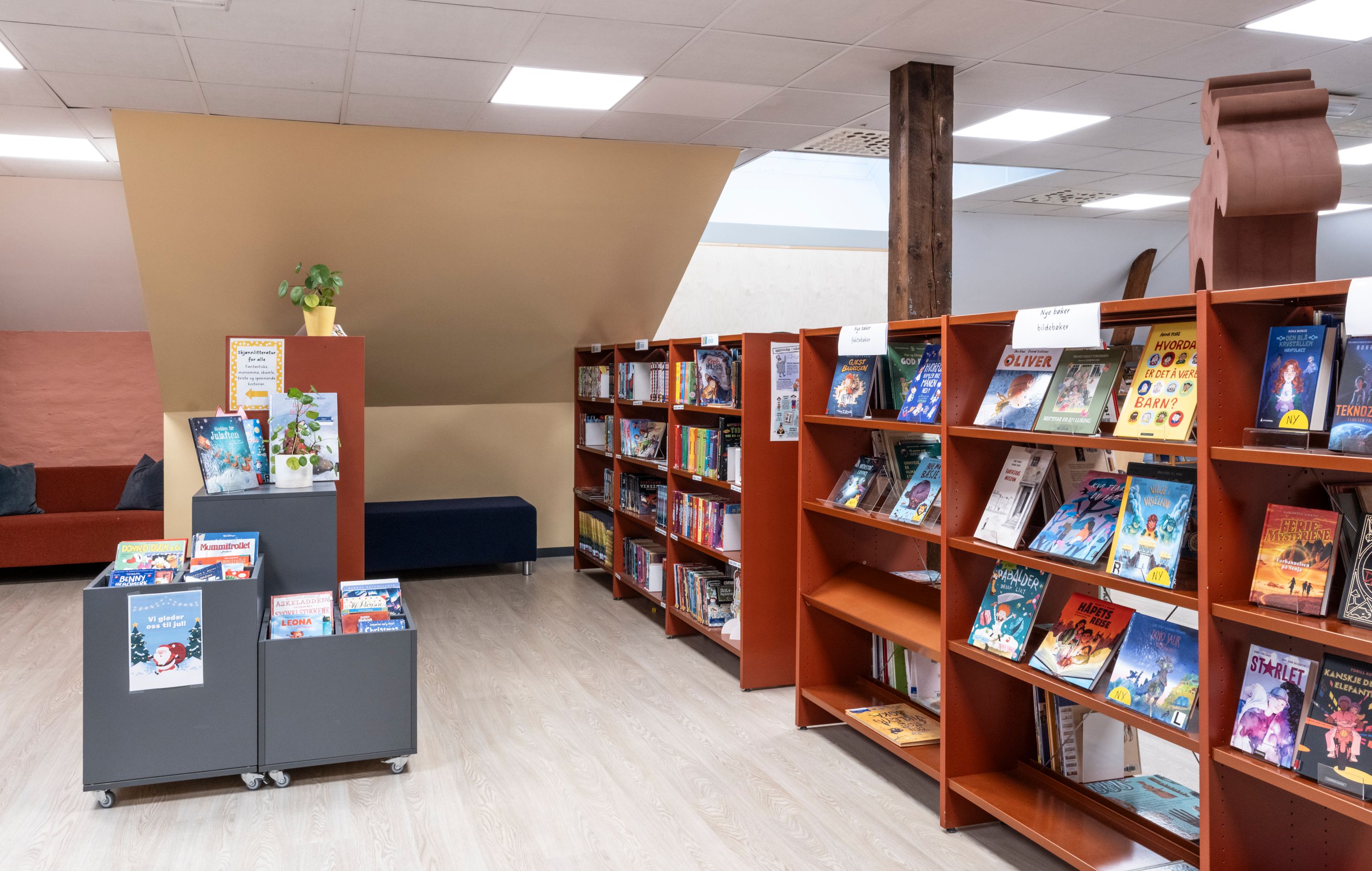 A modern library with rows of bookshelves, book display stands, and a couch and bench seating area.
