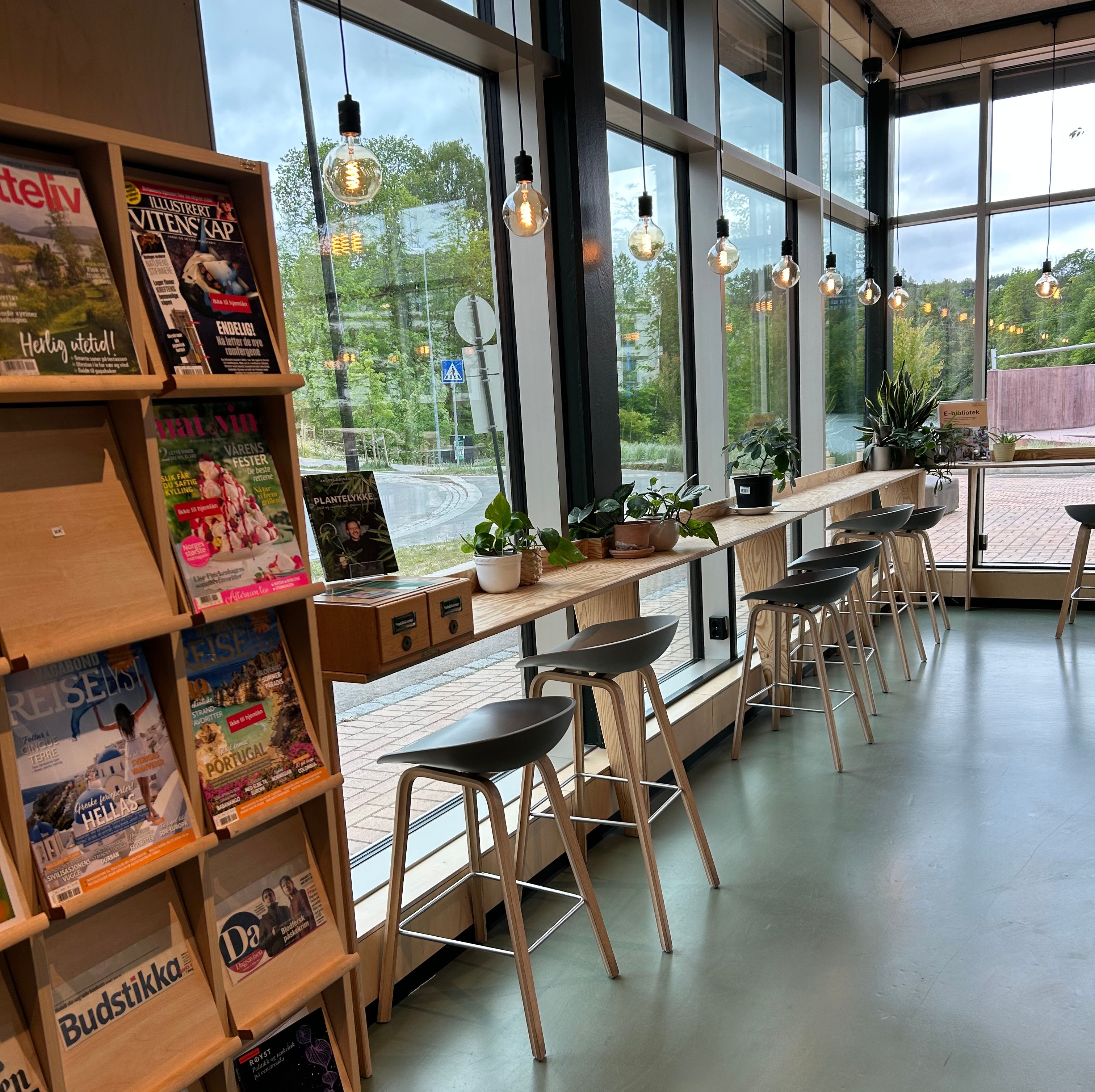 et bibliotek med et lang høybord foran store vinduer