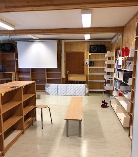 an empty room with shelves and a projector screen