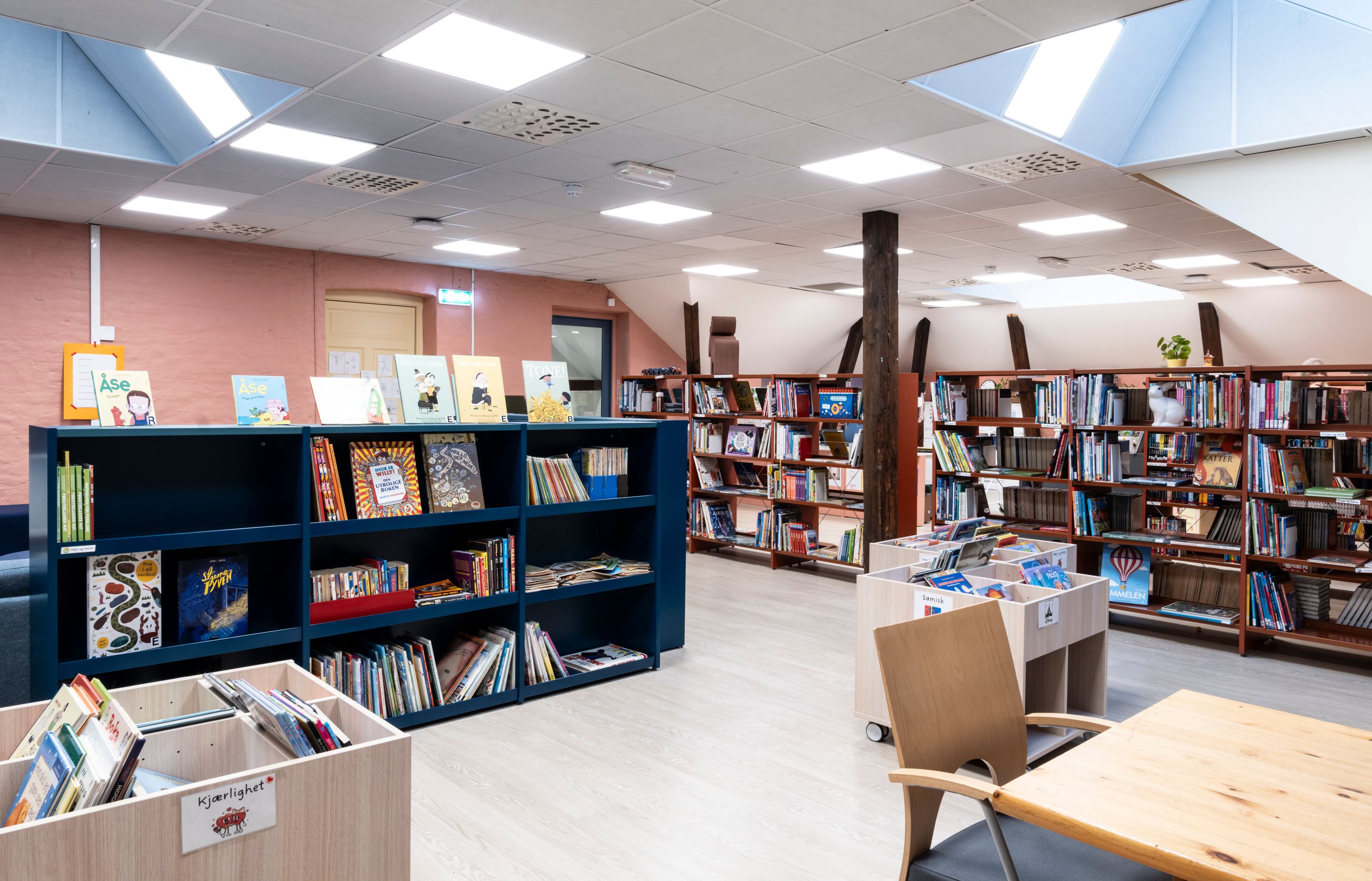 et skolebibliotek med fargerike bokreoler og skråtak