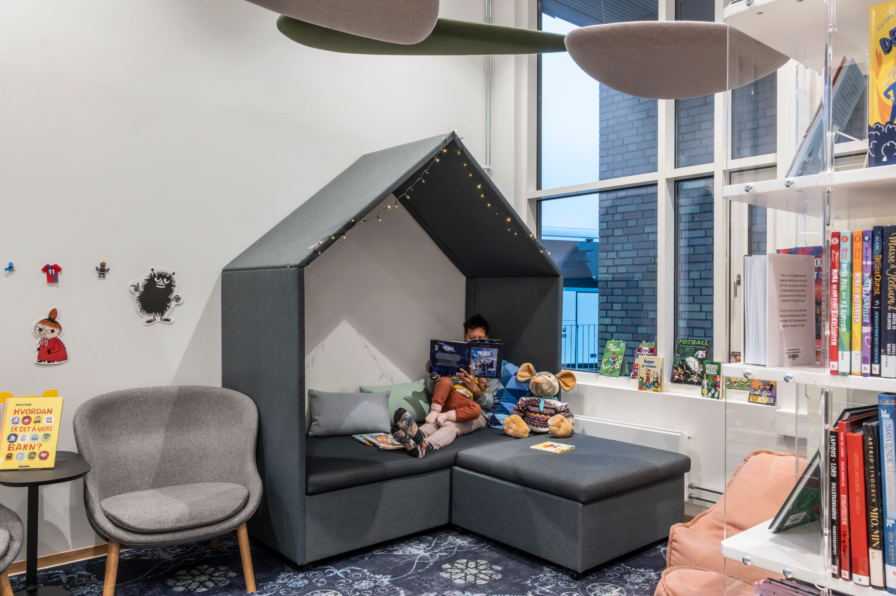 A child reads in a cozy, house-shaped reading nook in a hospital library.