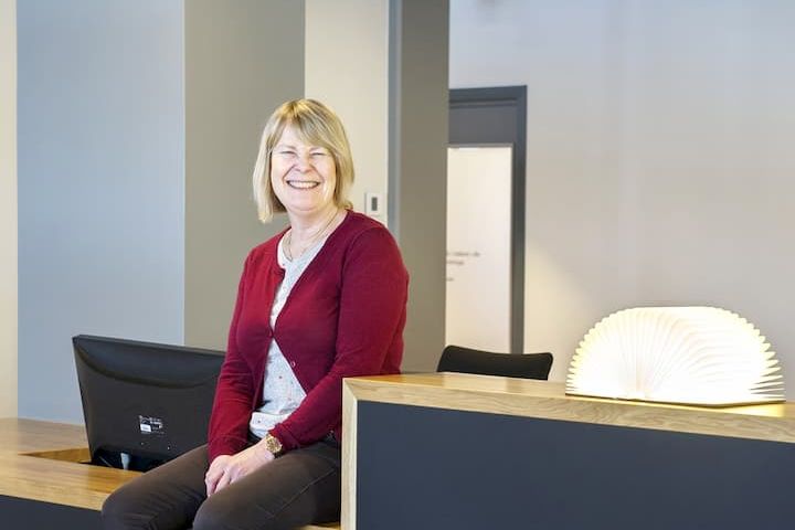 en kvinne i en rød genser sitter på en disk og smiler