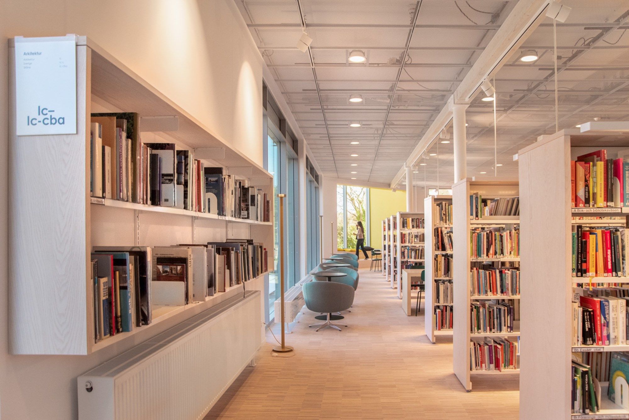 et bibliotek med bjørkefargede bokreoler langs vegg og på gulvet