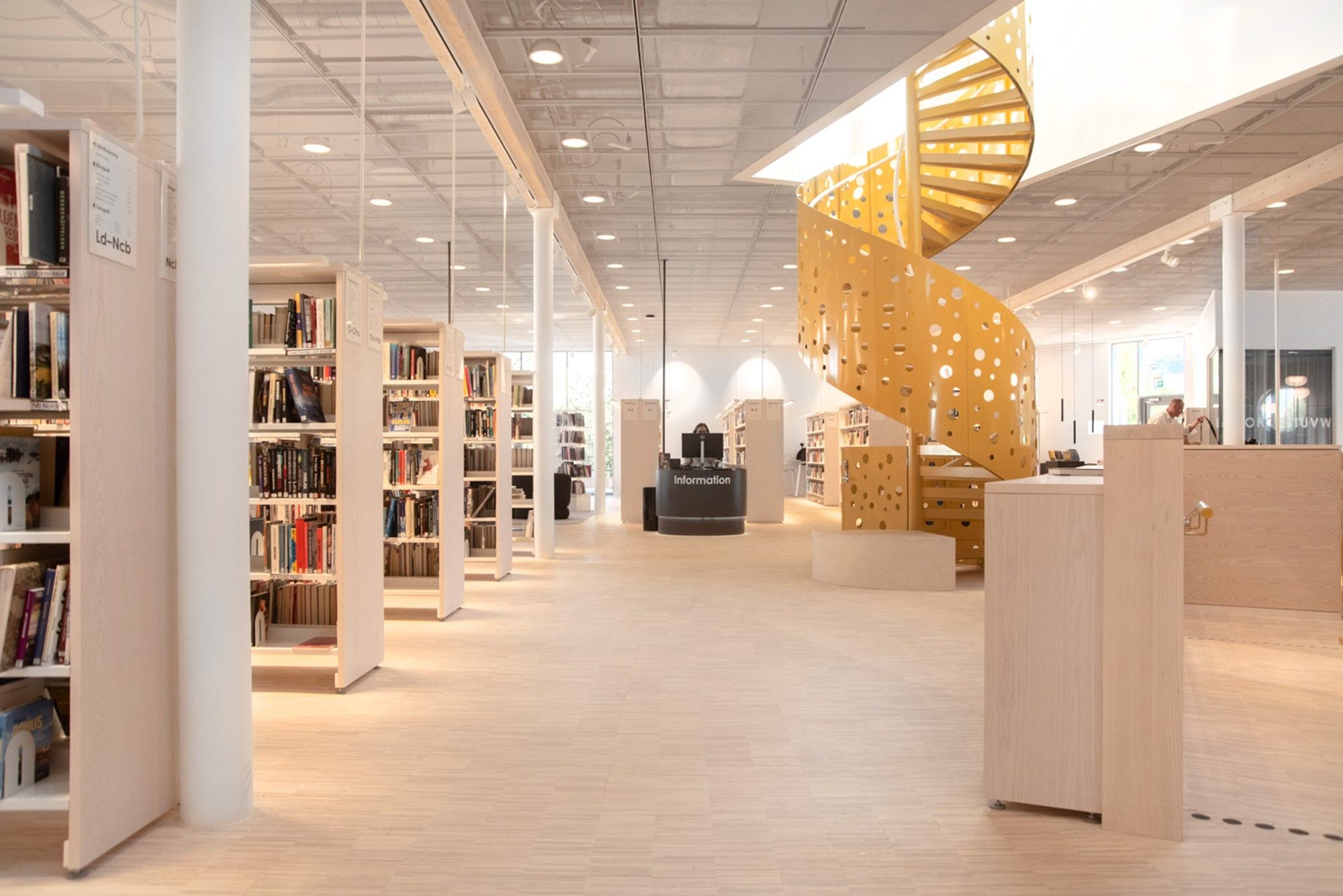 et bibliotek med mange reoler og en gul vindeltrapp