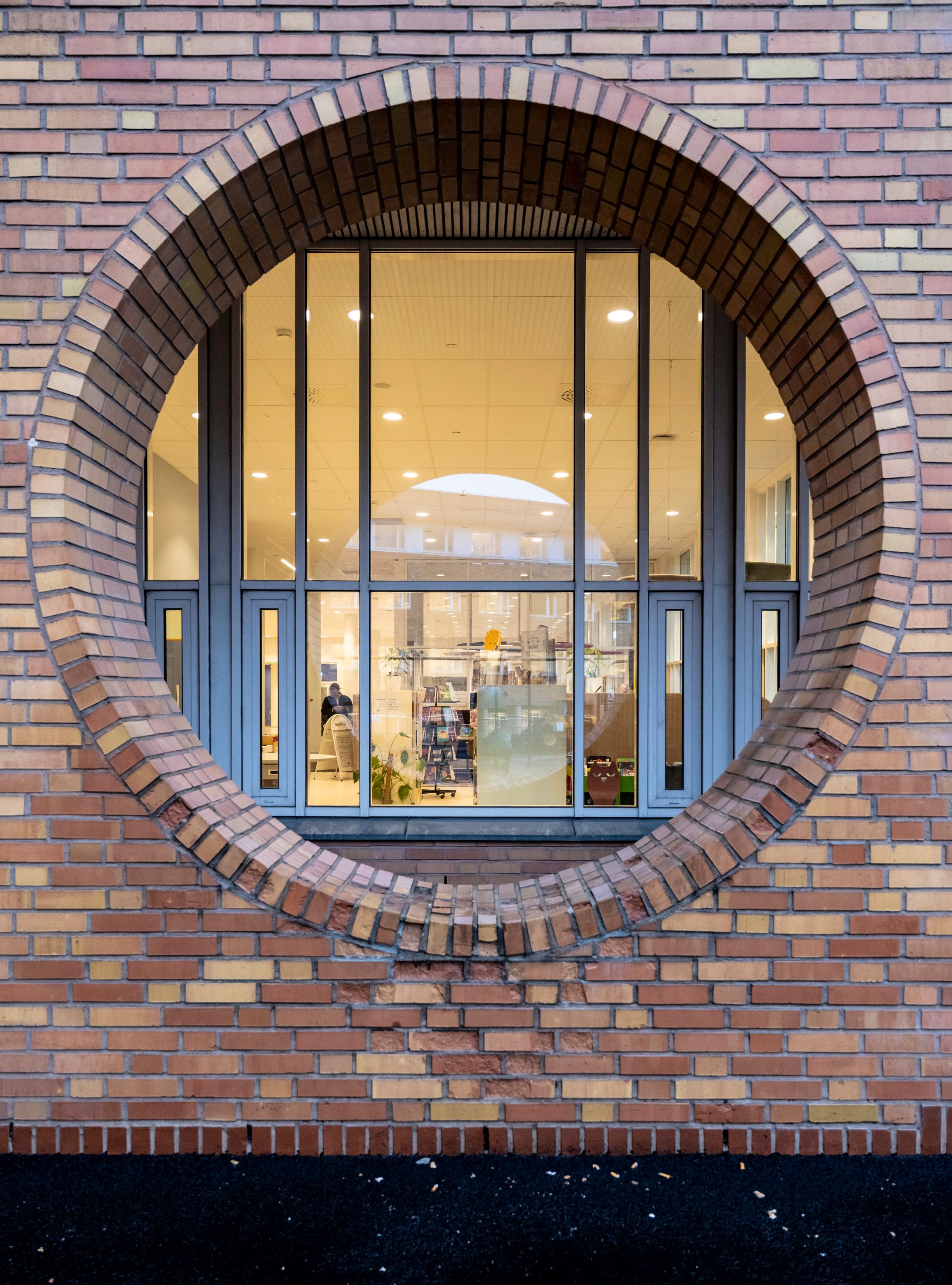 A circular window framed by bricks, looking into a library