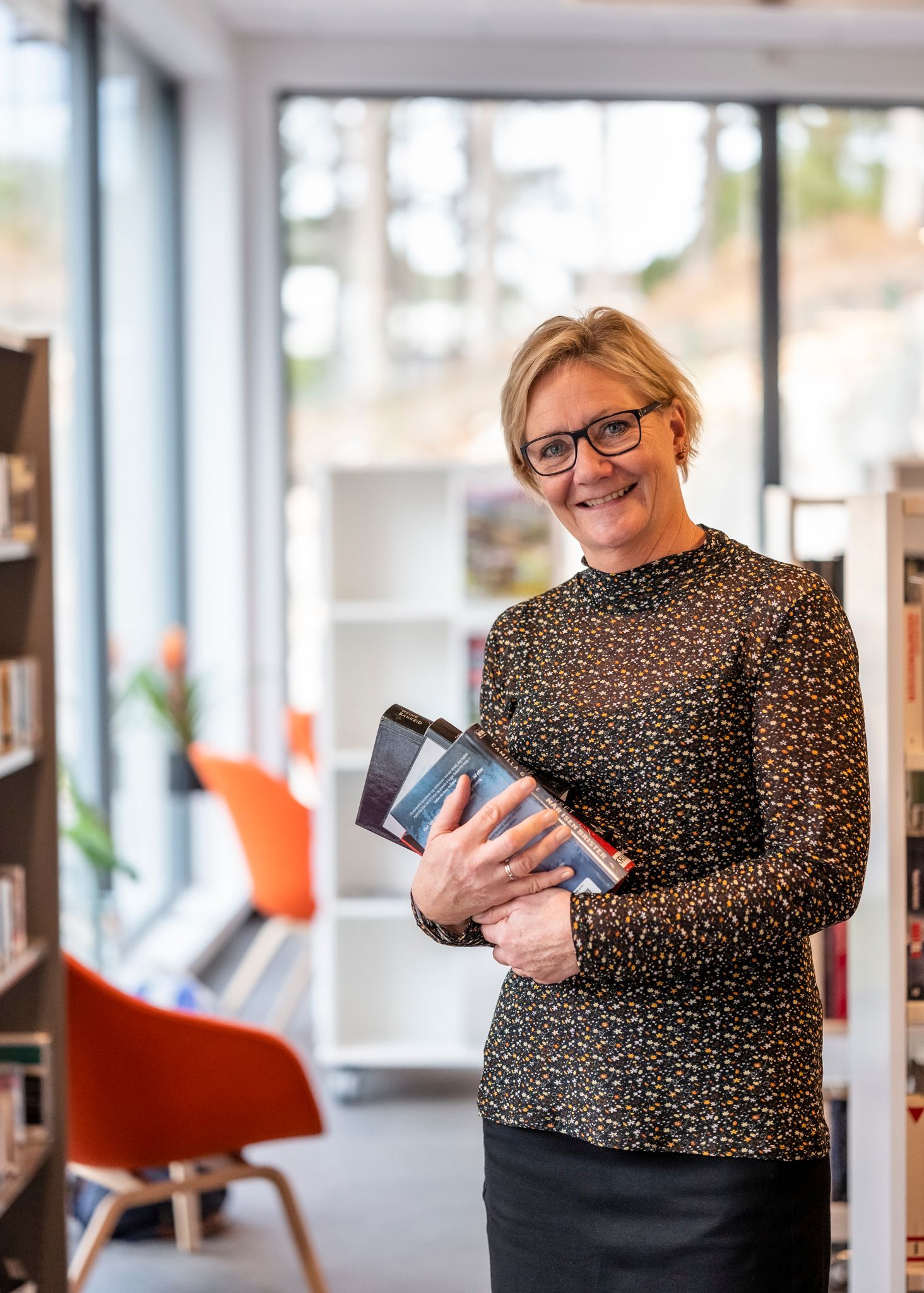 biblioteksjefen i audnedal holder en bok i hendene sine i biblioteket.
