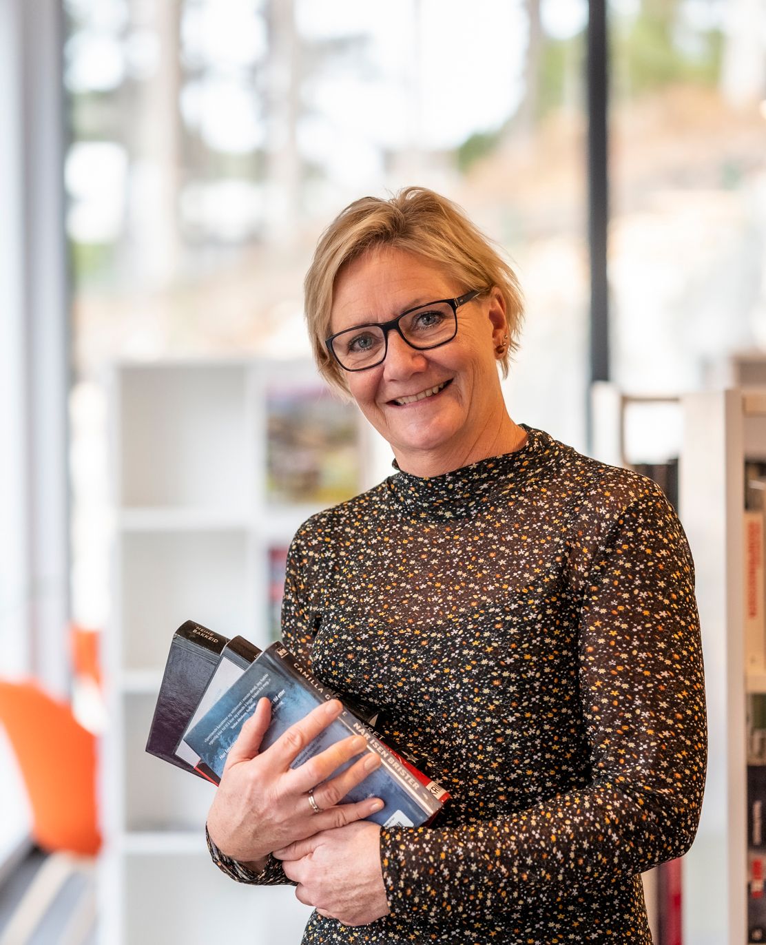 biblioteksjefen i audnedal holder en bok i hendene sine i biblioteket.
