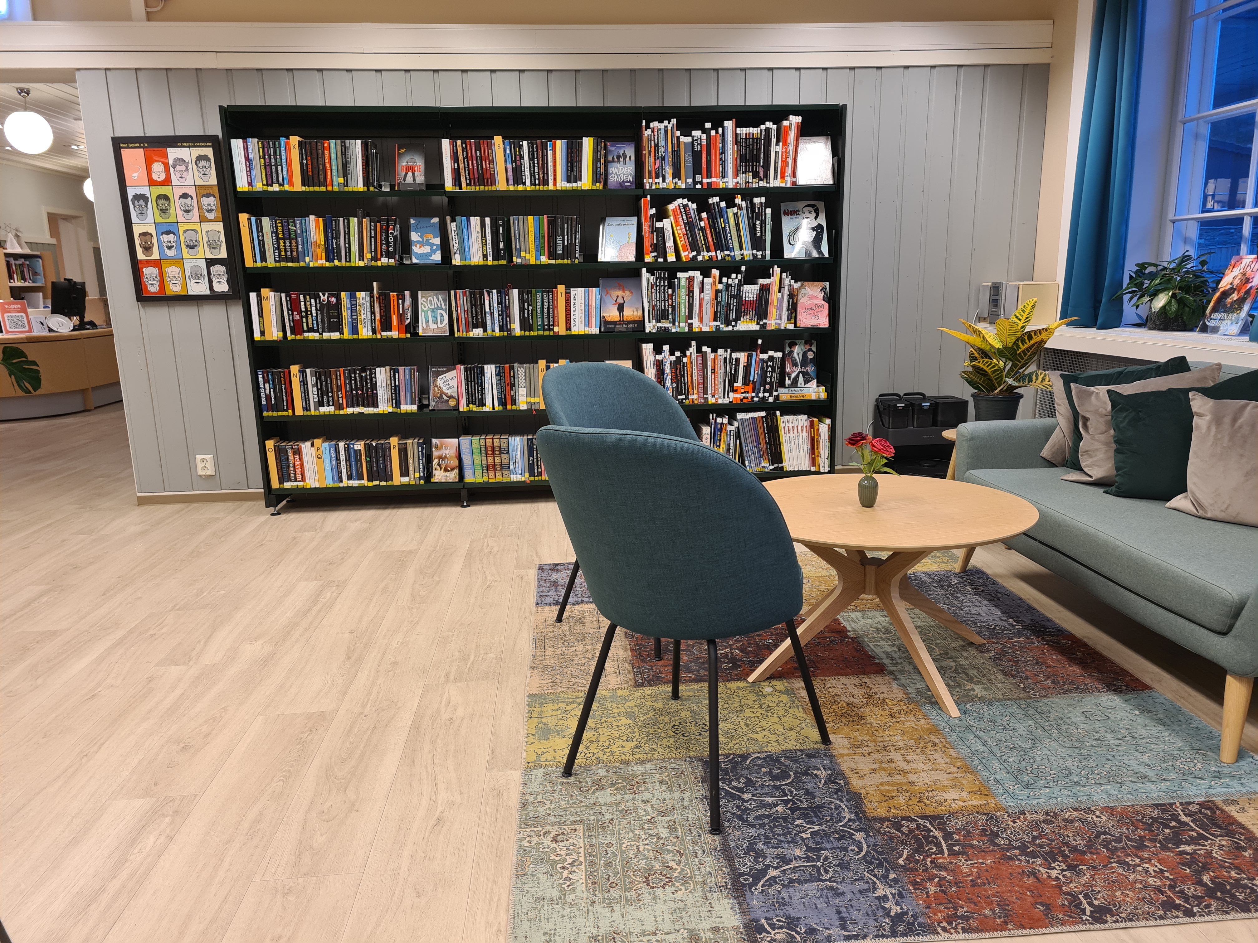 et hyggelig rom med en svart bokreol langs vegg og en sittegruppe i varme farger