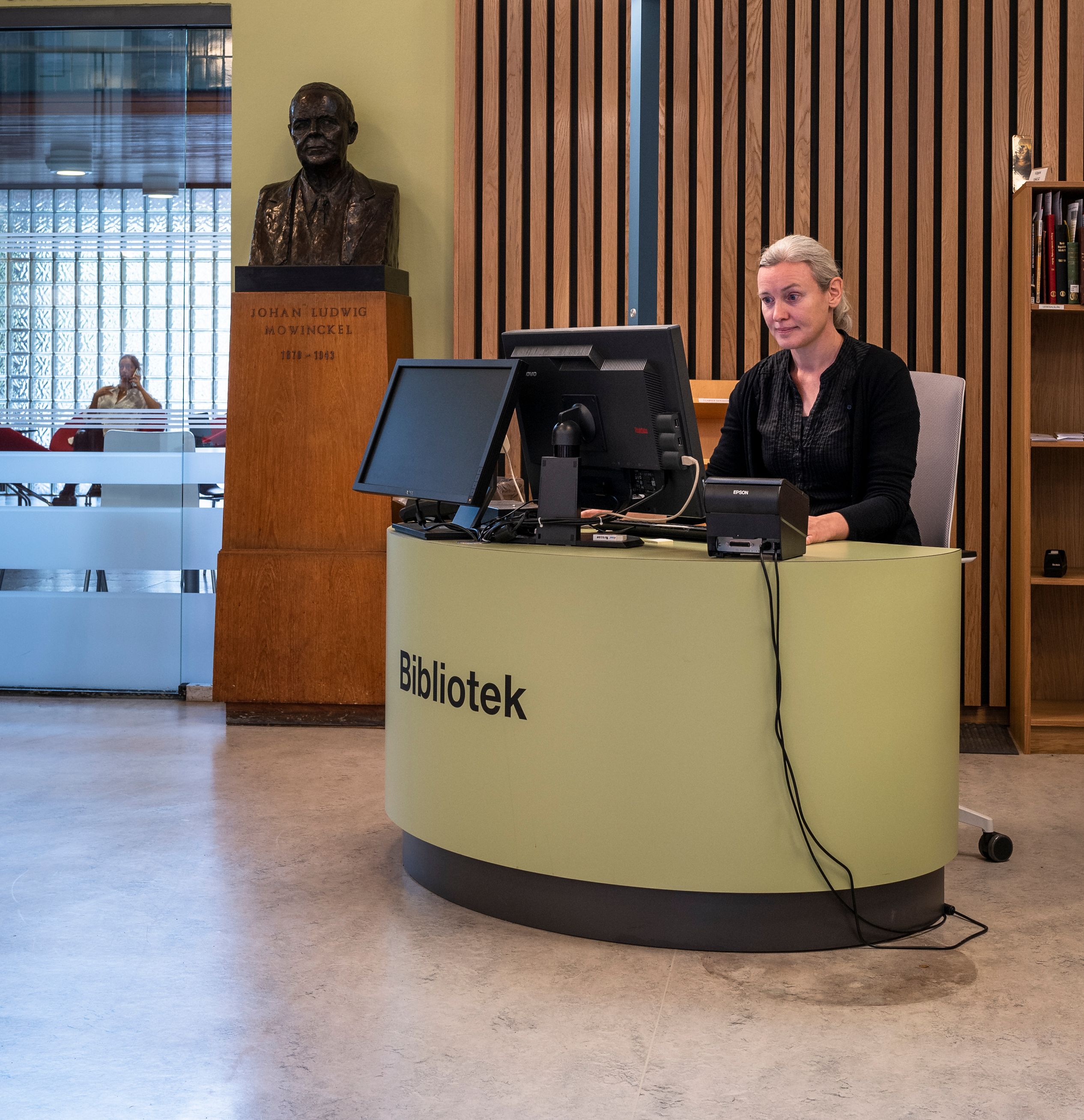 en kvinne sitter ved et skrivebord med ordet bibliotek på det