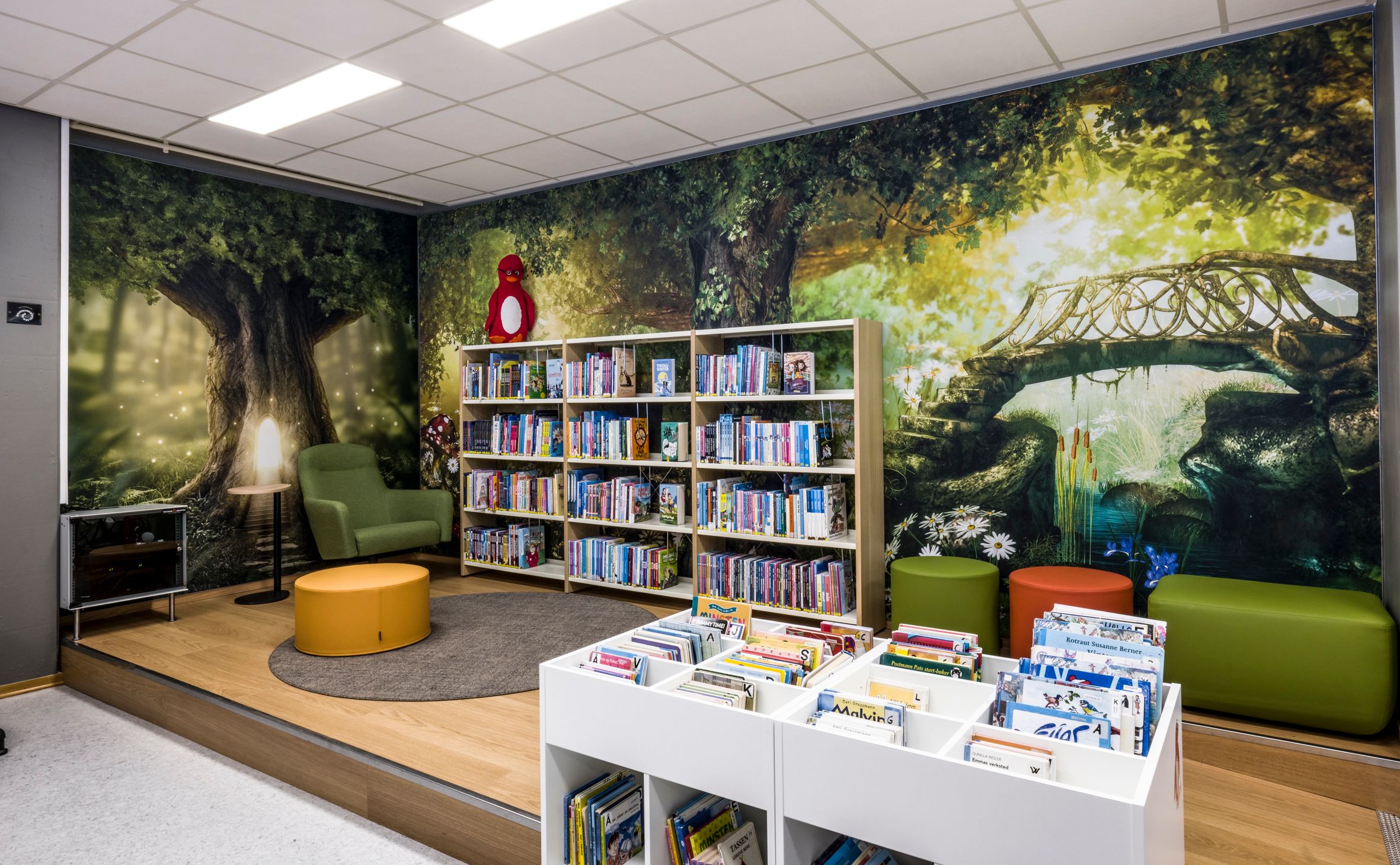 et bibliotek med et stort veggmaleri på veggen og mange bøker på hyllene.