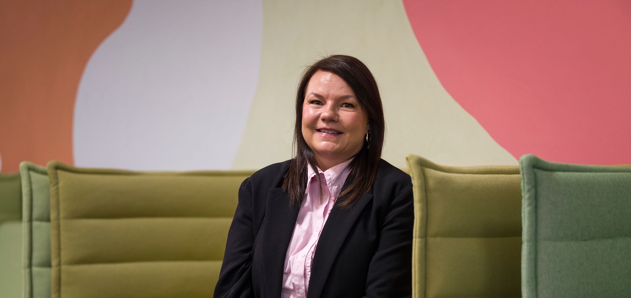 en kvinne i dress sitter på en grønn sofa.