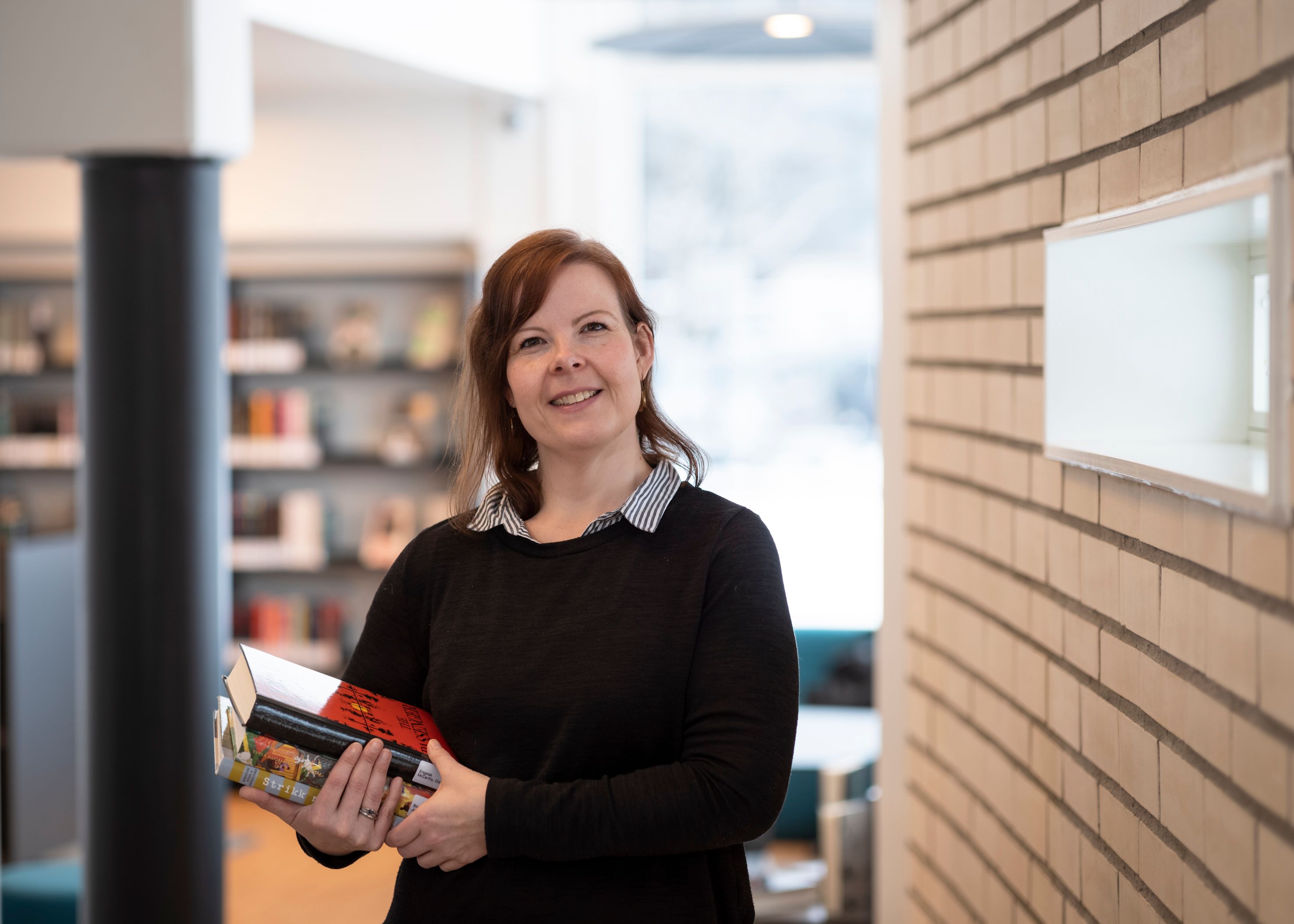 en kvinne holder en bok i hendene sine i et bibliotek.