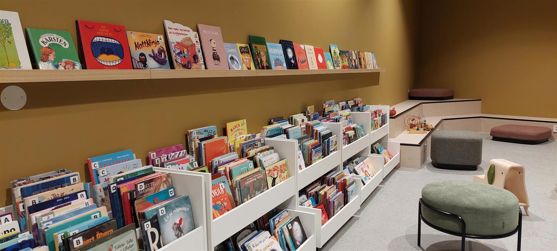 A colorful children's library with books on display and various soft seating options.