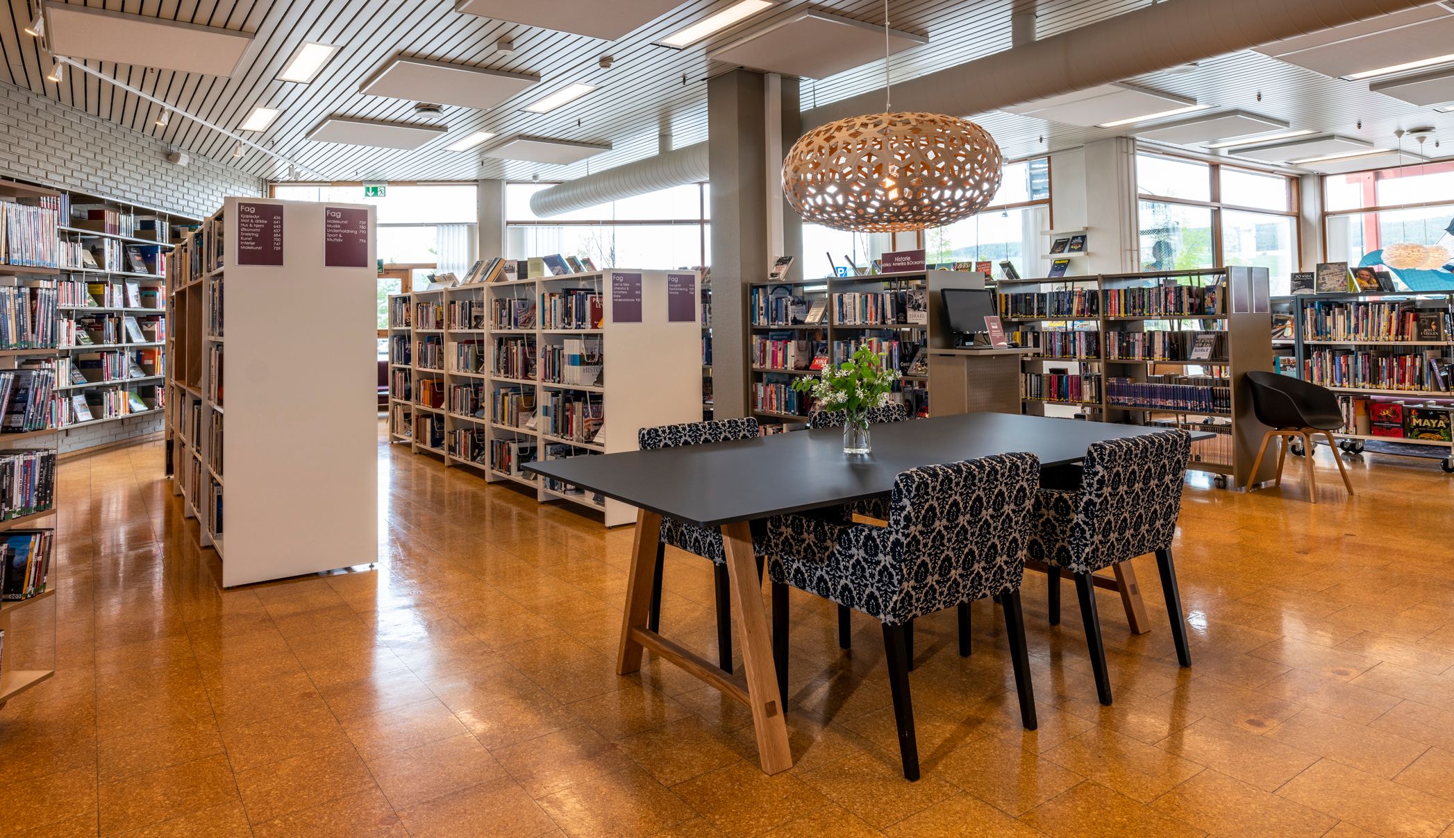 en sittegruppe står midt i et bibliotek med hvite bokreoler.