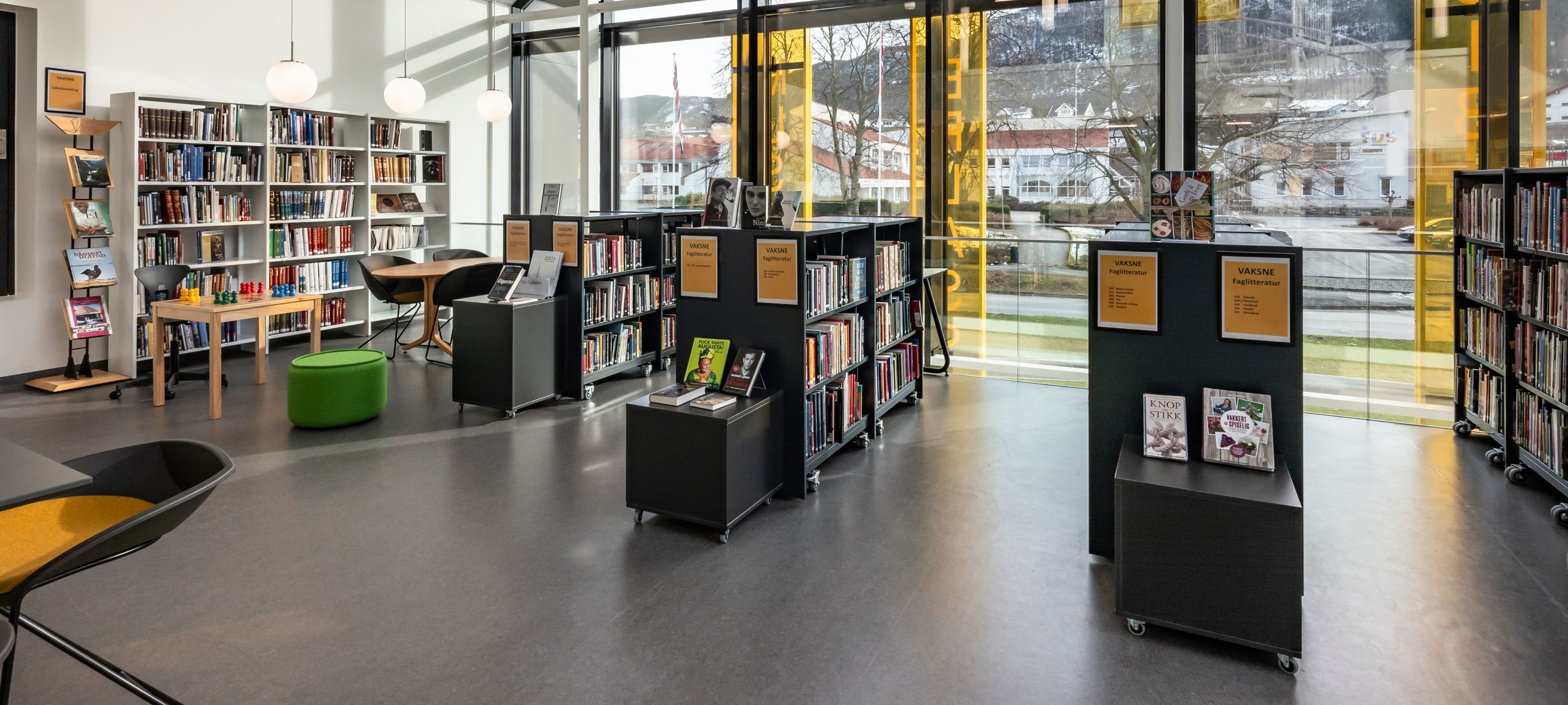 et bibliotek med mange bøker på hyllene og skilting på reolene