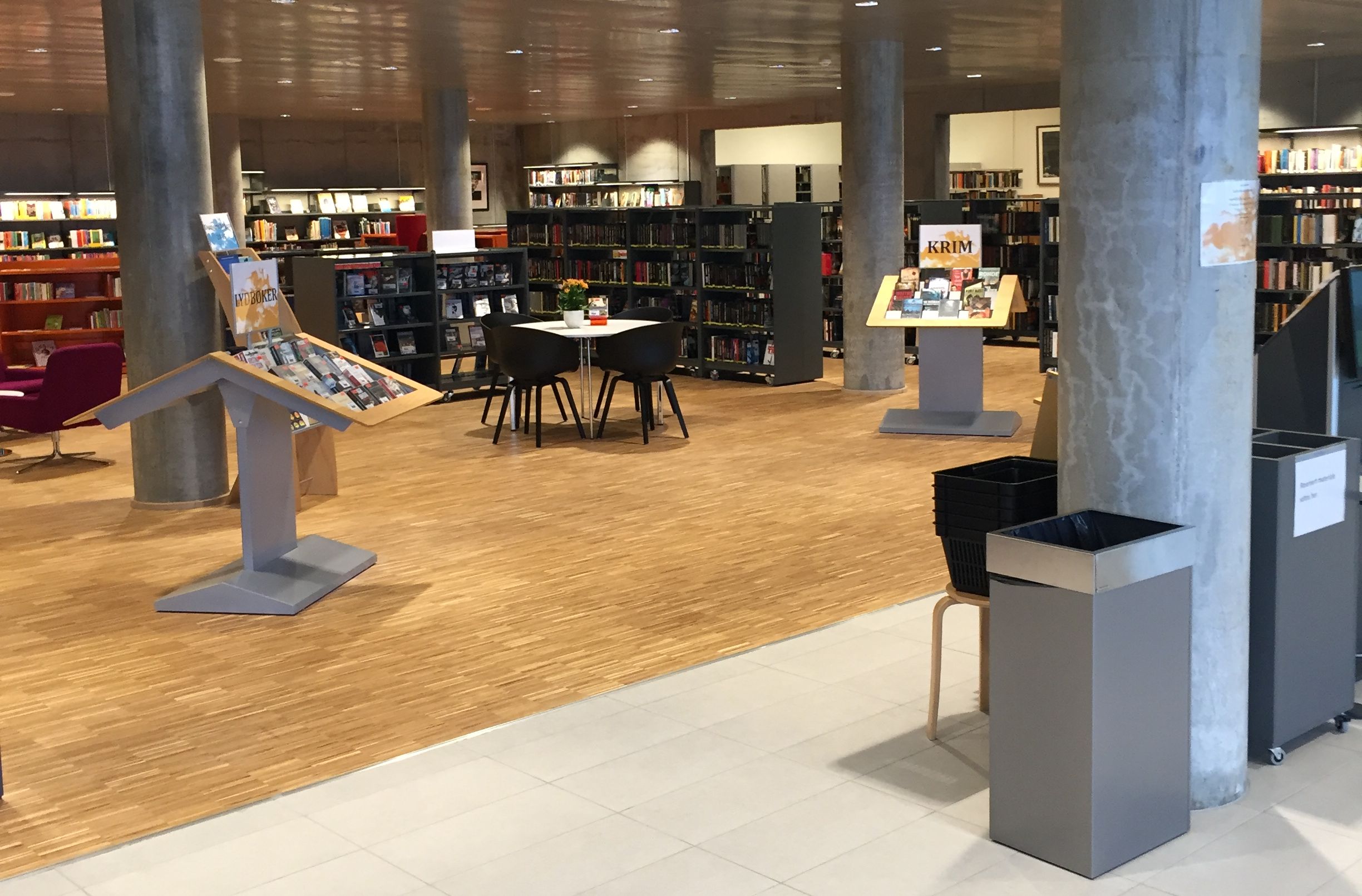 et bibliotek med et bord og stoler i midten av det