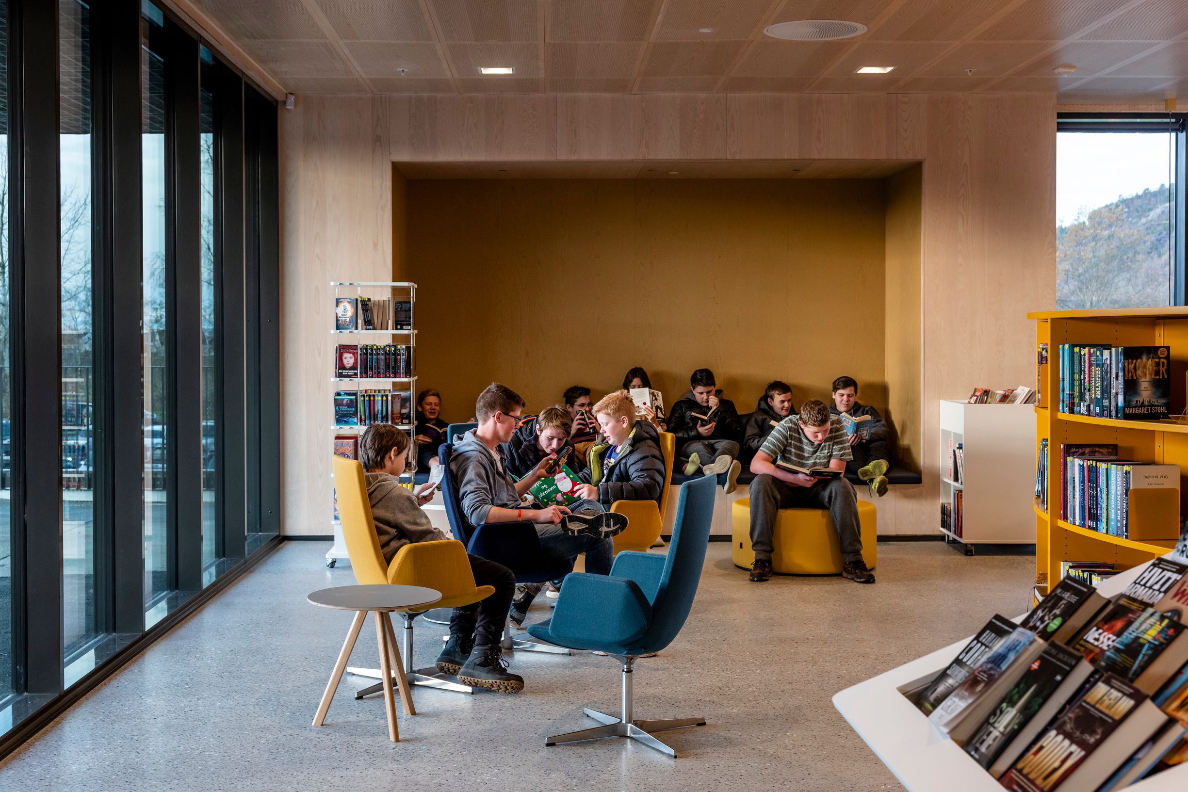 Students reading and relaxing in a modern library with large windows.
