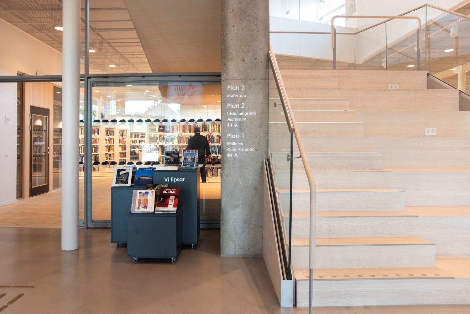 tre utstillingspodier står ved inngangen til et bibliotek