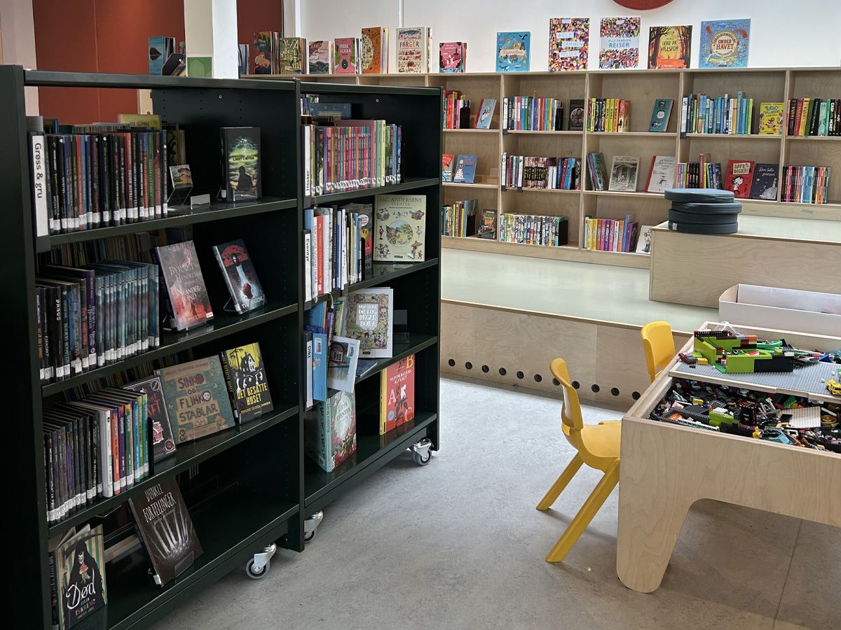 et bibliotek med lave bokreoler og barnemøbler