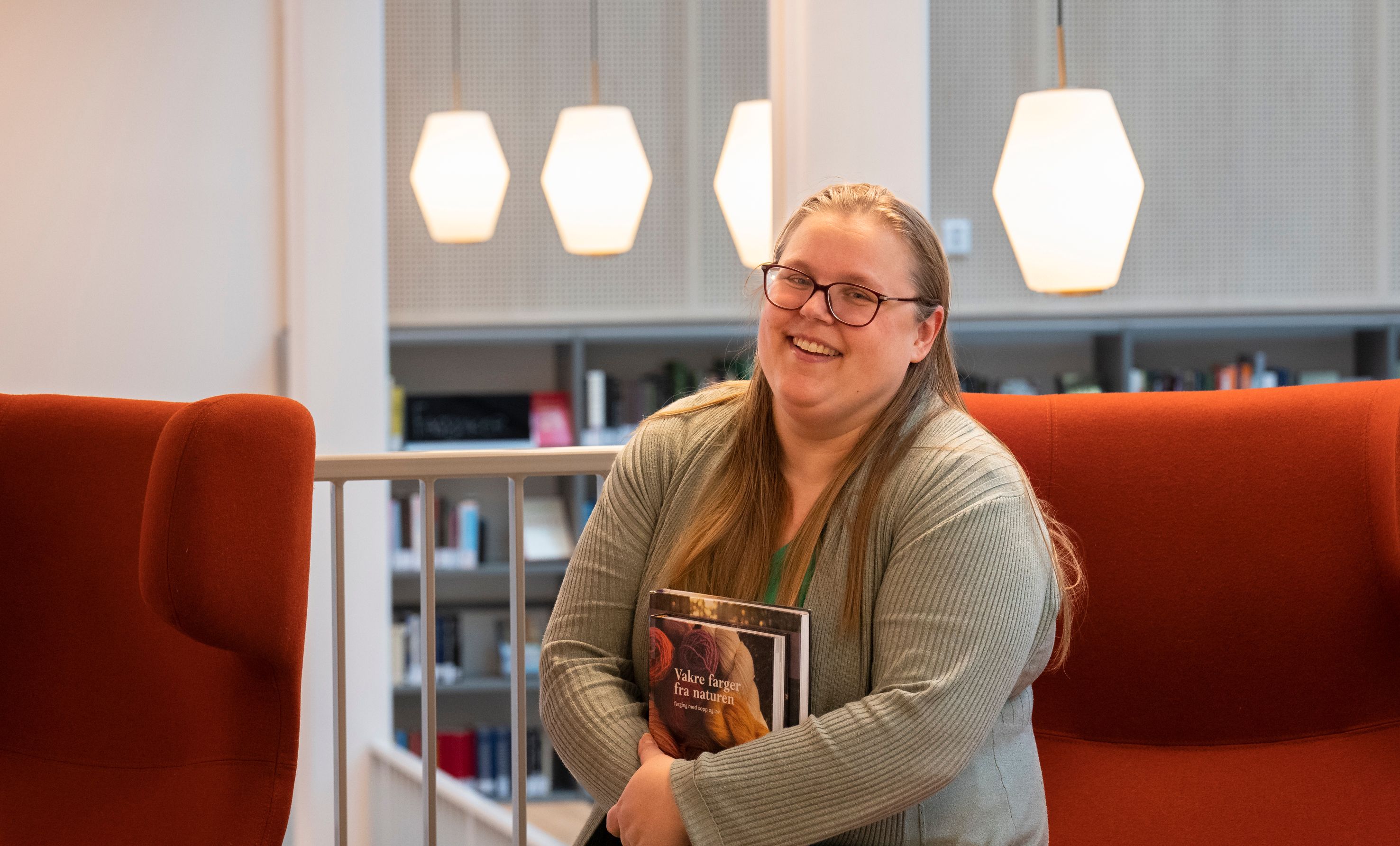 en kvinne sitter ved et skrivebord på et bibliotek.