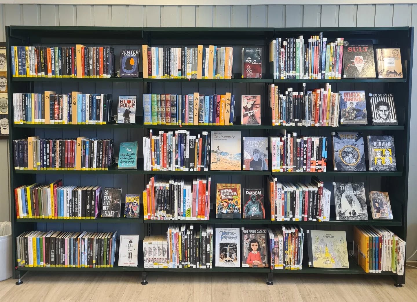 A dark green bookshelf densely packed with various books.