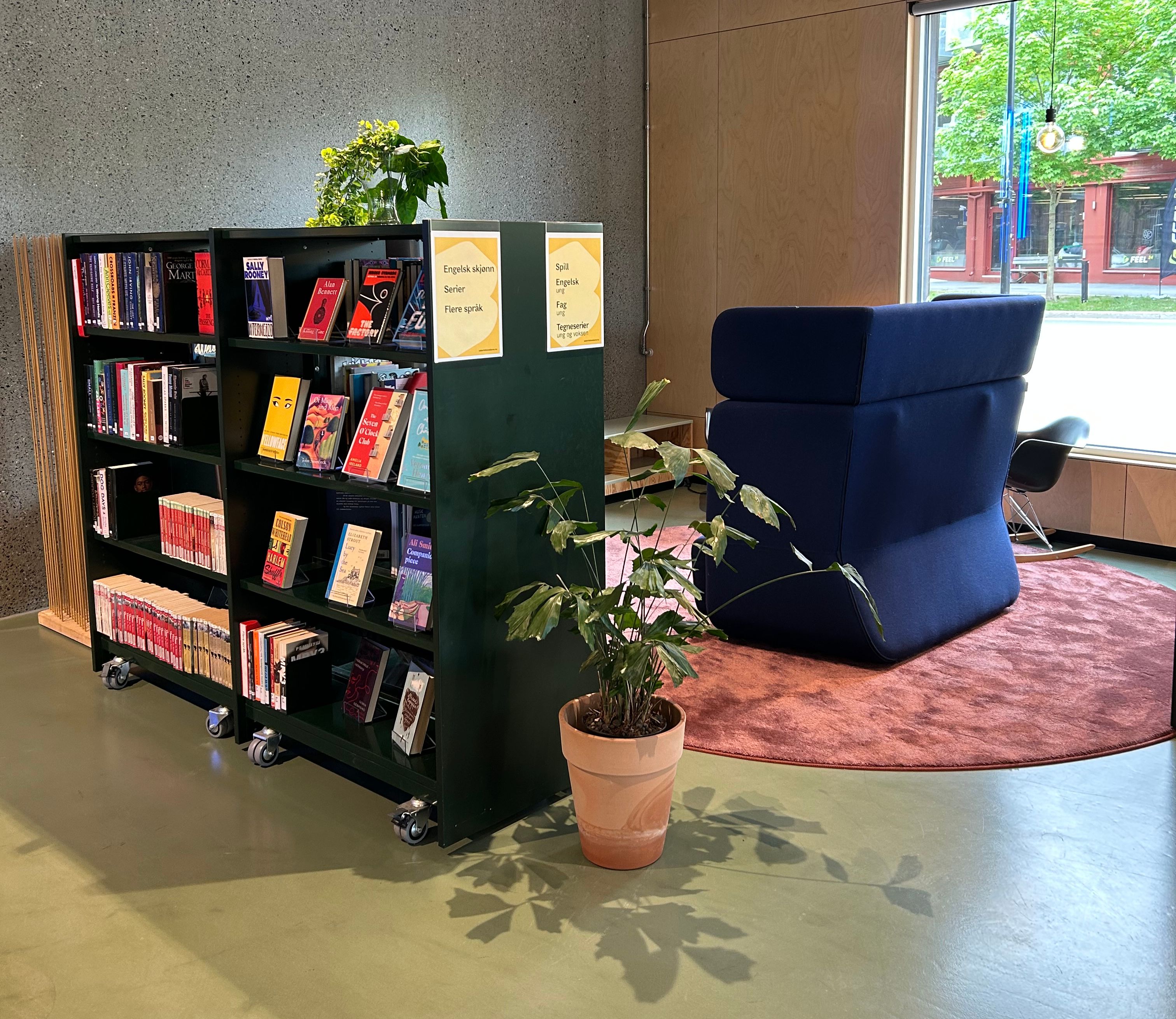 et bibliotek med en bokreol på hjul og en blå sofa med høy rygg