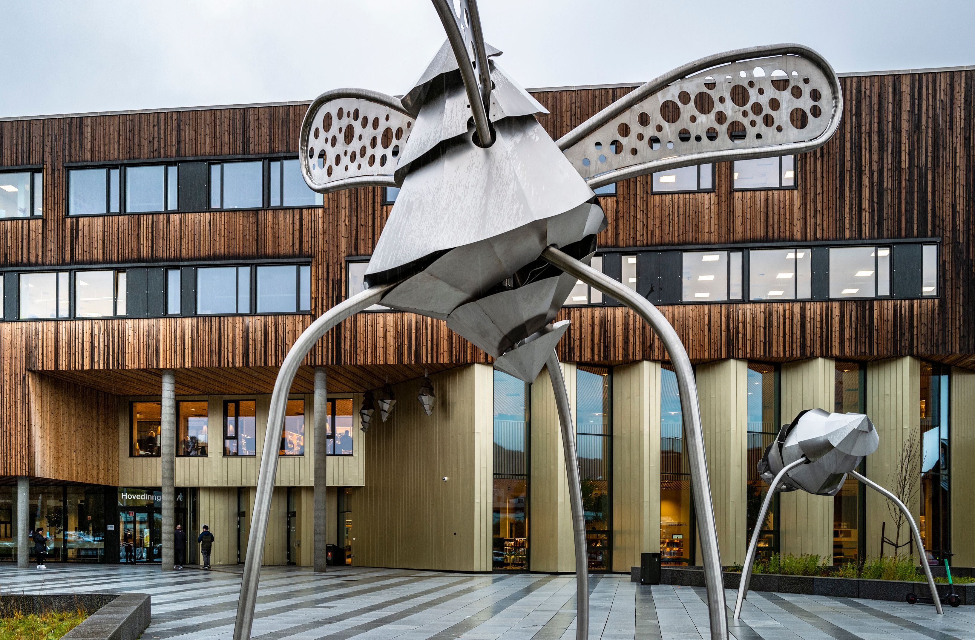 en stor metallskulptur av en bie er foran en stor trebygning.