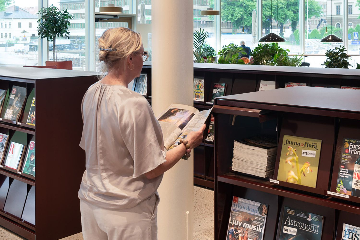 en dame står og leser i et tidsskrift på et bibliotek