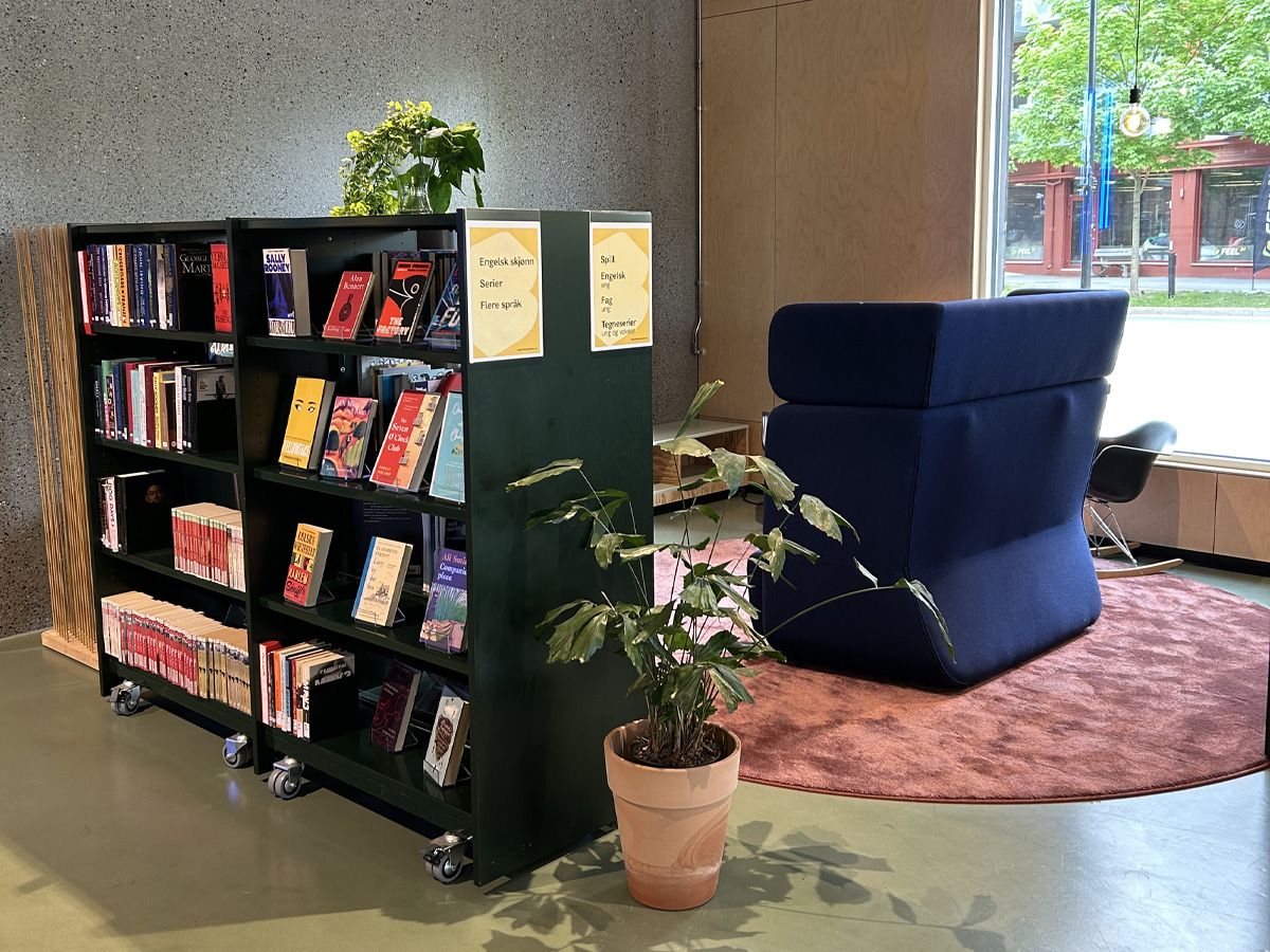 et bibliotek med en bokreol på hjul og en blå sofa med høy rygg