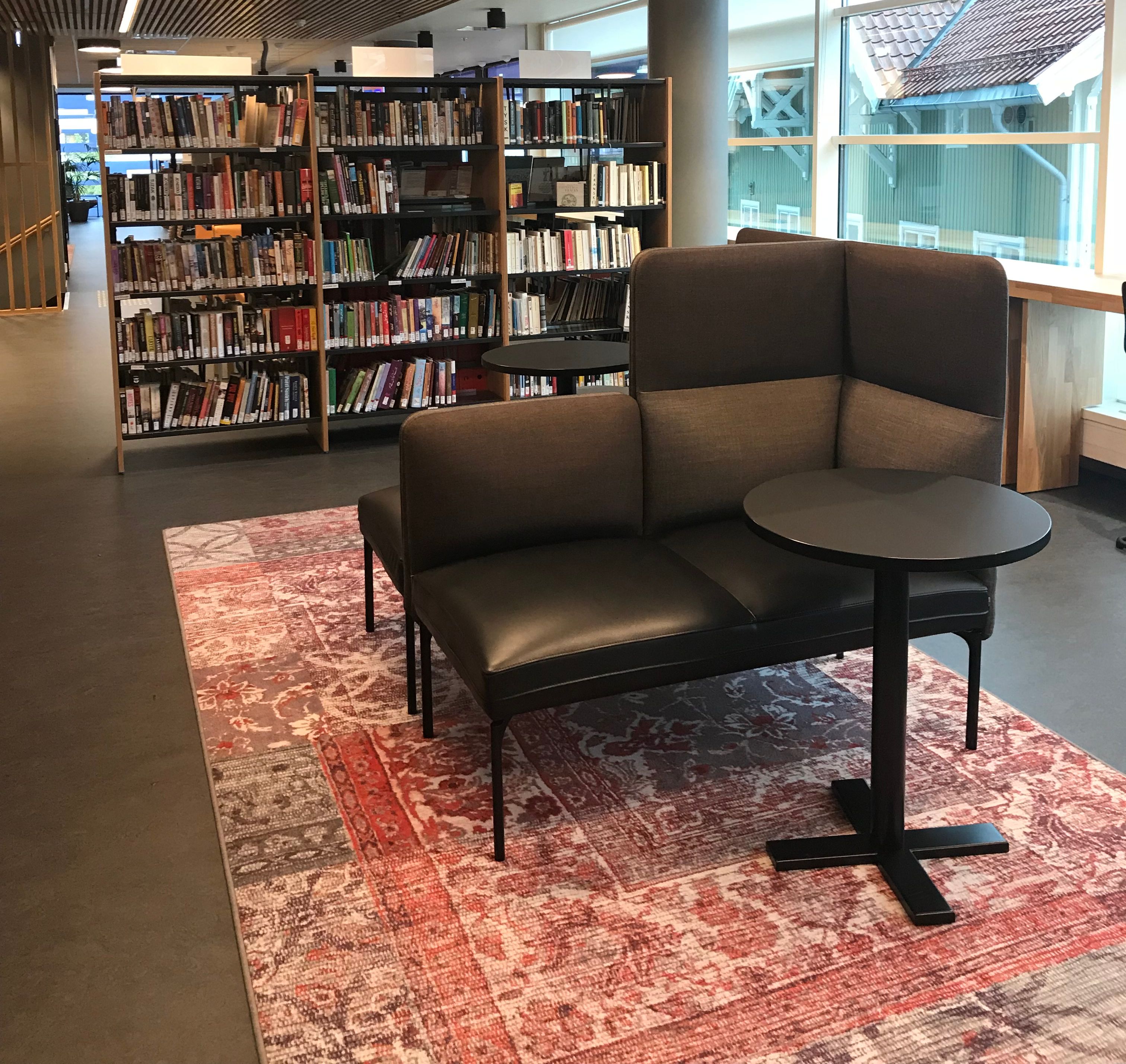 et bibliotek med en sofa og et bord foran bokhyller