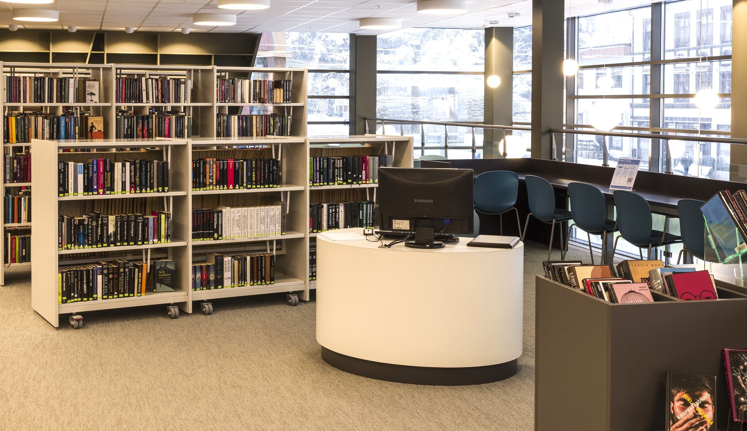 en hvit bibliotekskranke står midt i rommet med en pc på